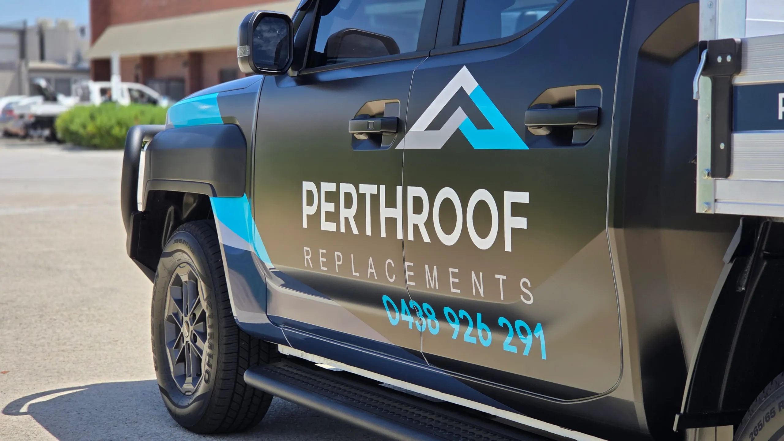 PerthRoof Replacements logo and cyan lettering across the satin black Kia Tasman doors