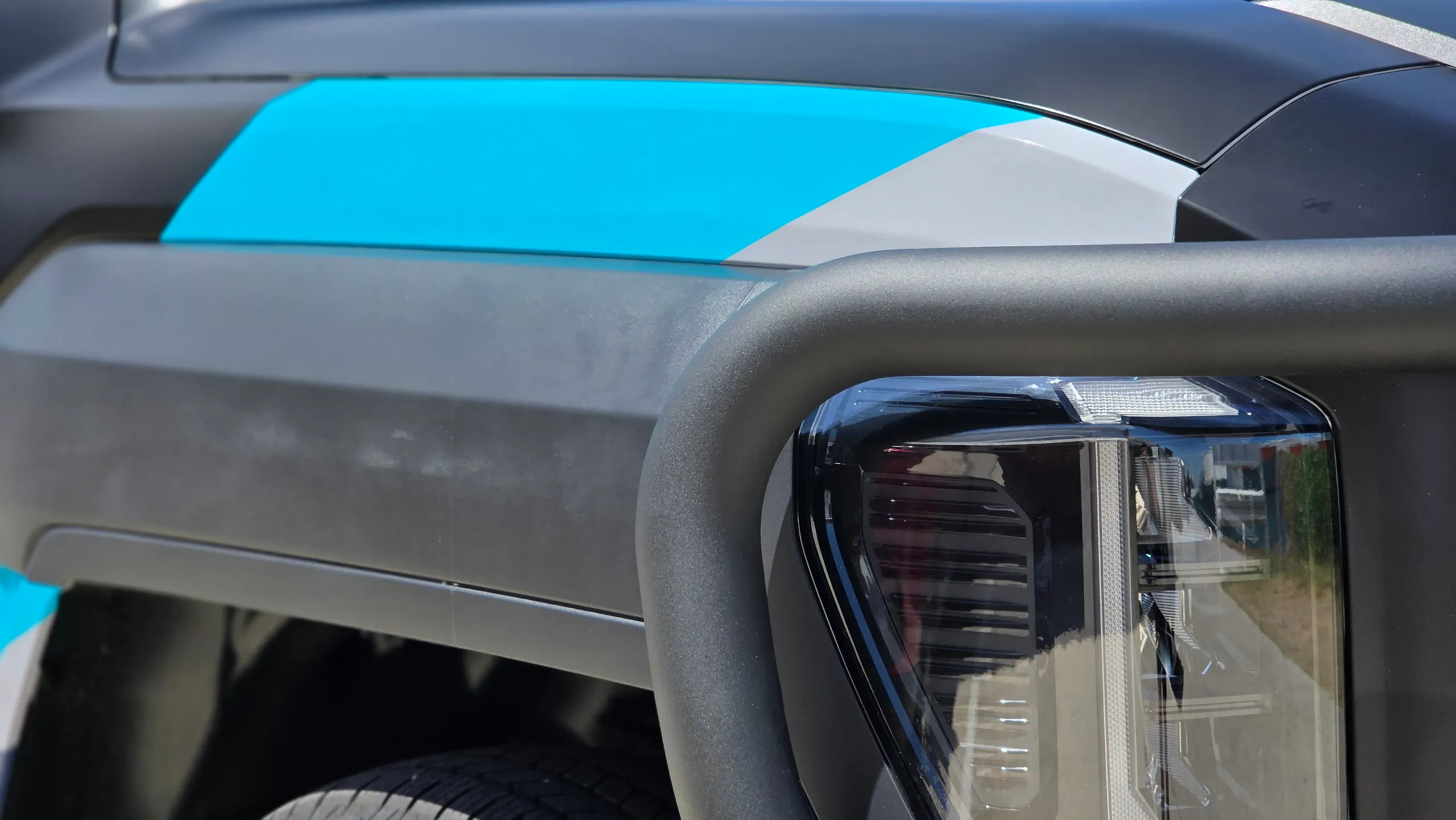 Cyan and grey graphics across the Kia Tasman front guard above the headlight