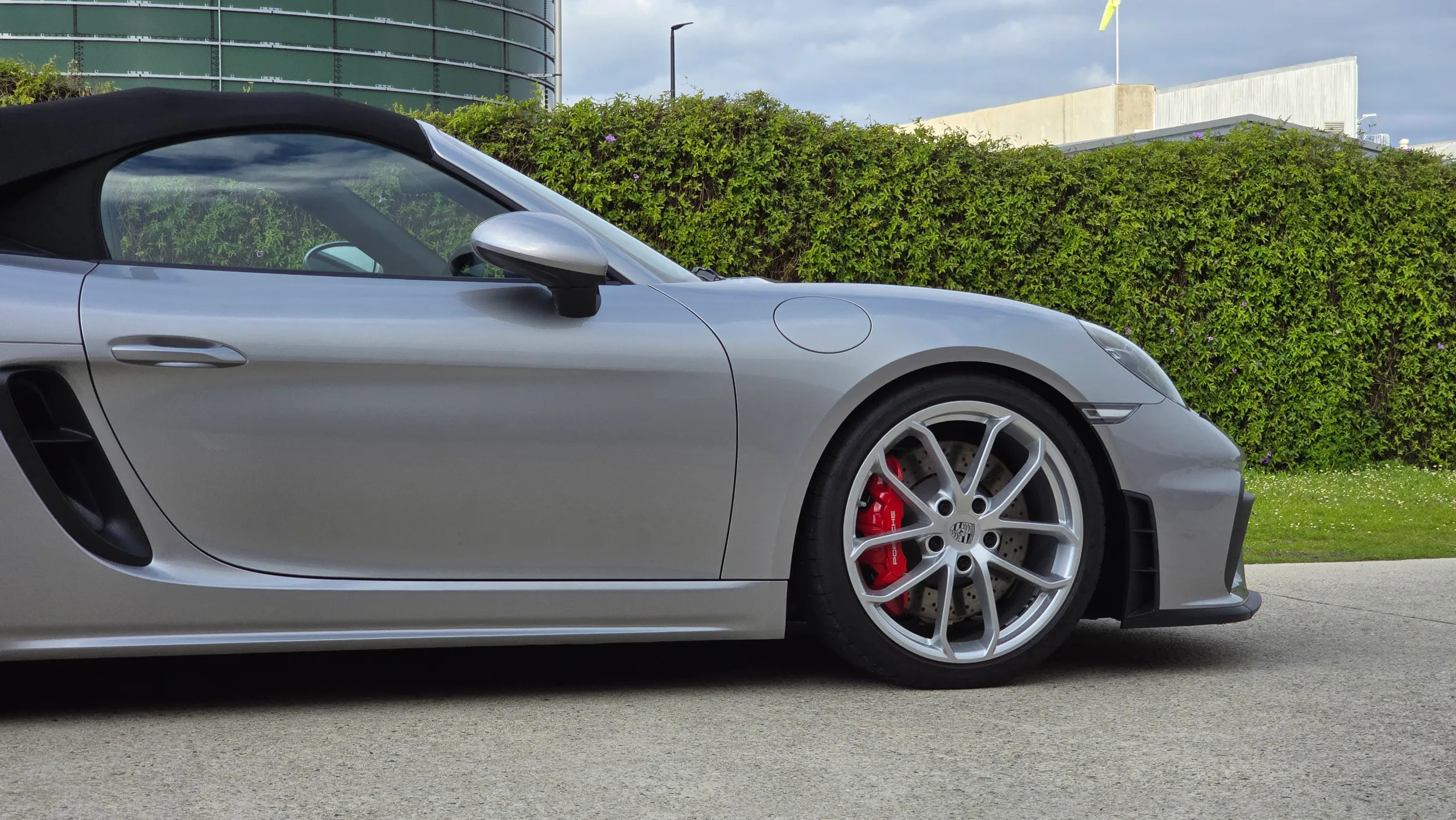 Side detail of the silver Porsche 718 Spyder with a black roof and red brake calipers