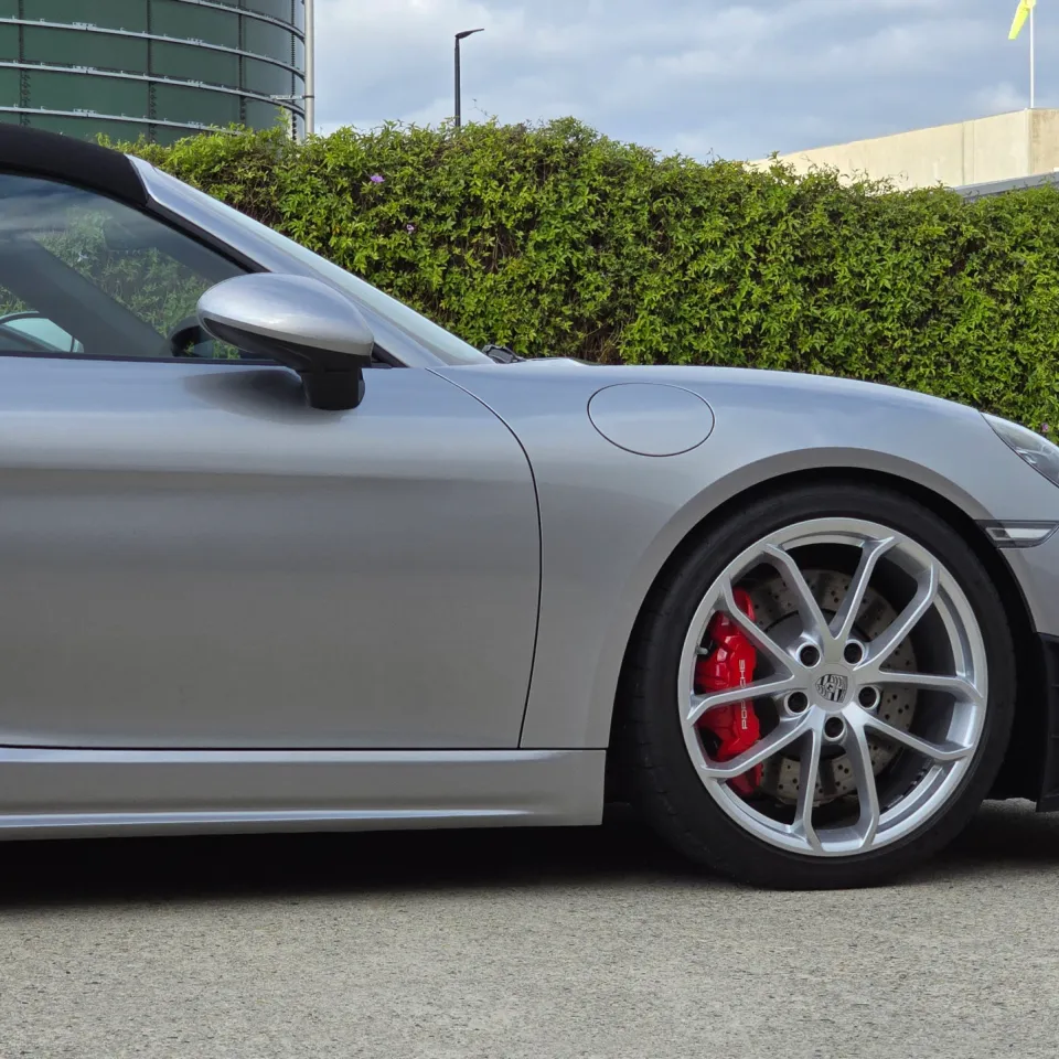 Side detail of the silver Porsche 718 Spyder with a black roof and red brake calipers