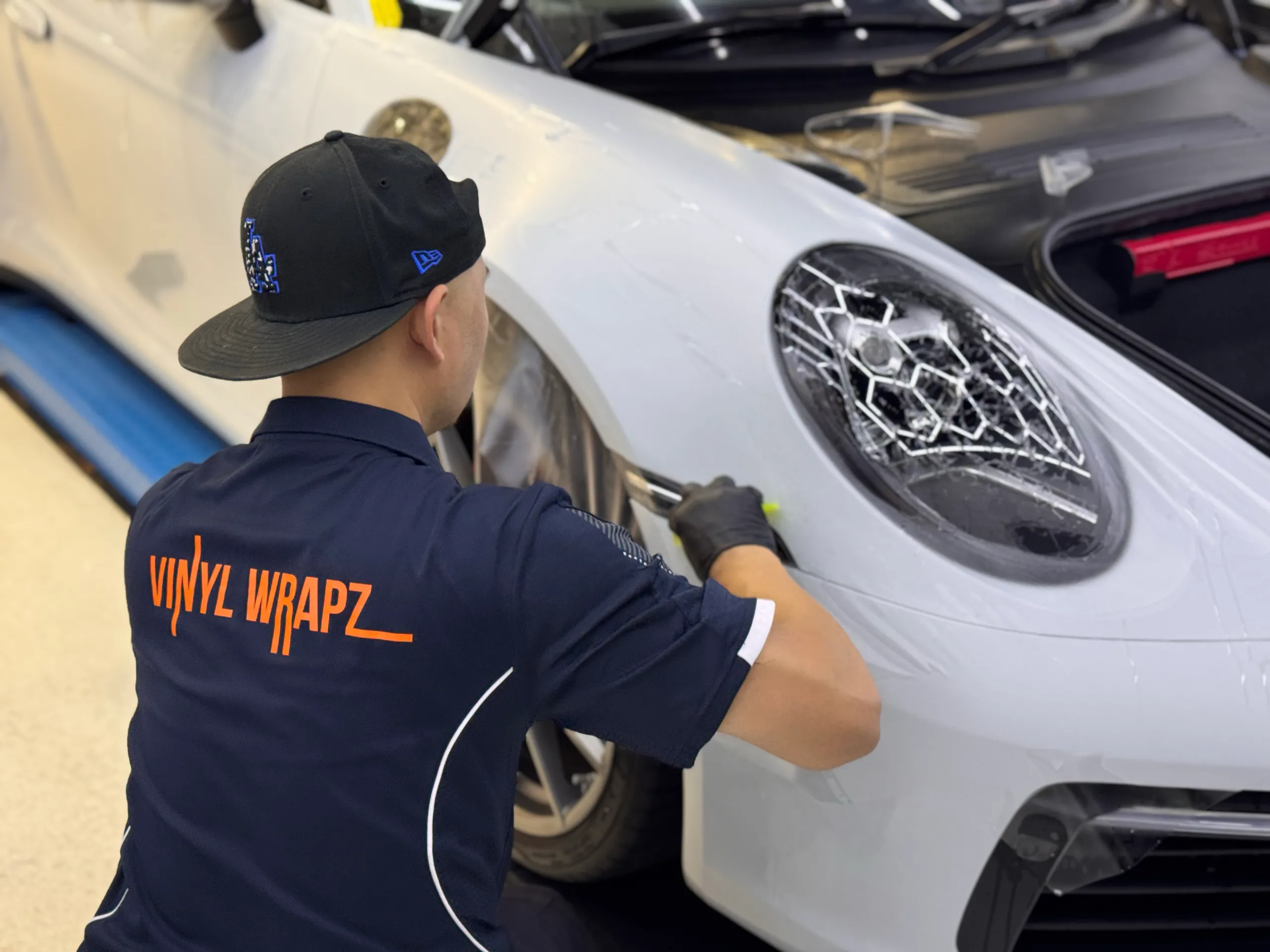 Installer smoothing film on the white Porsche 911 front guard