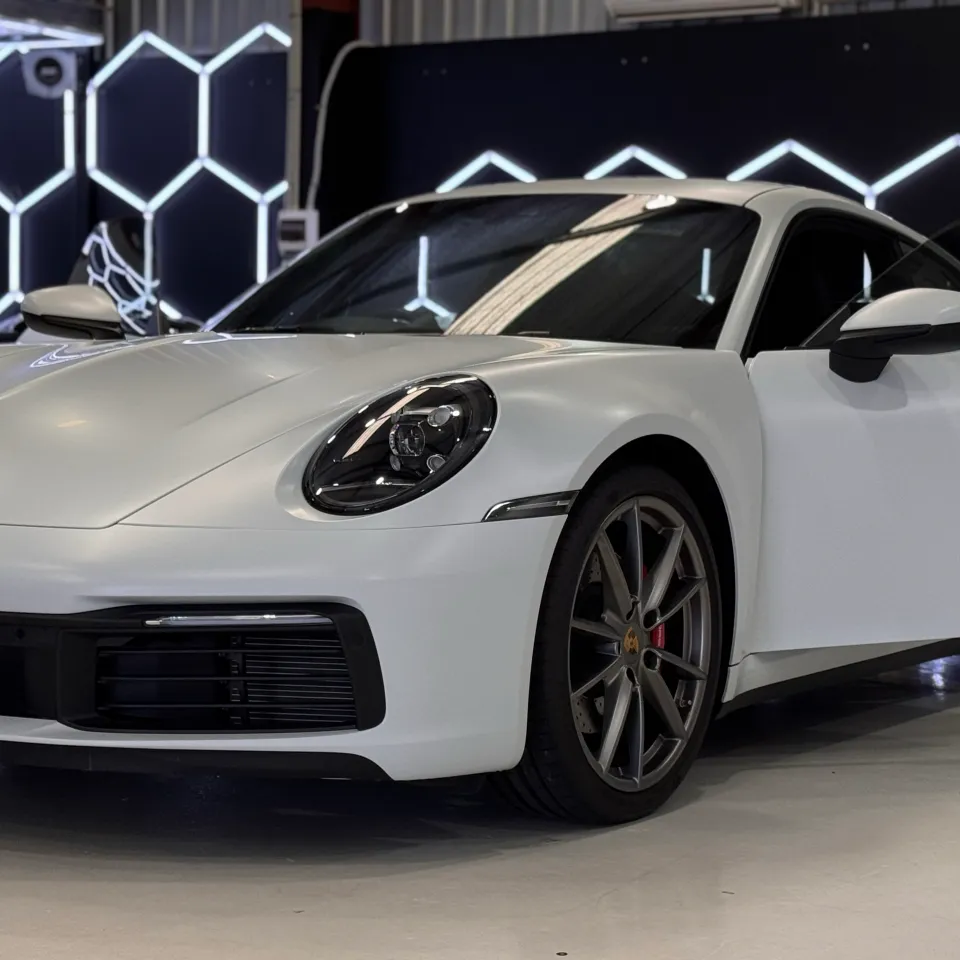 White Porsche 911 front quarter in the workshop with a door open