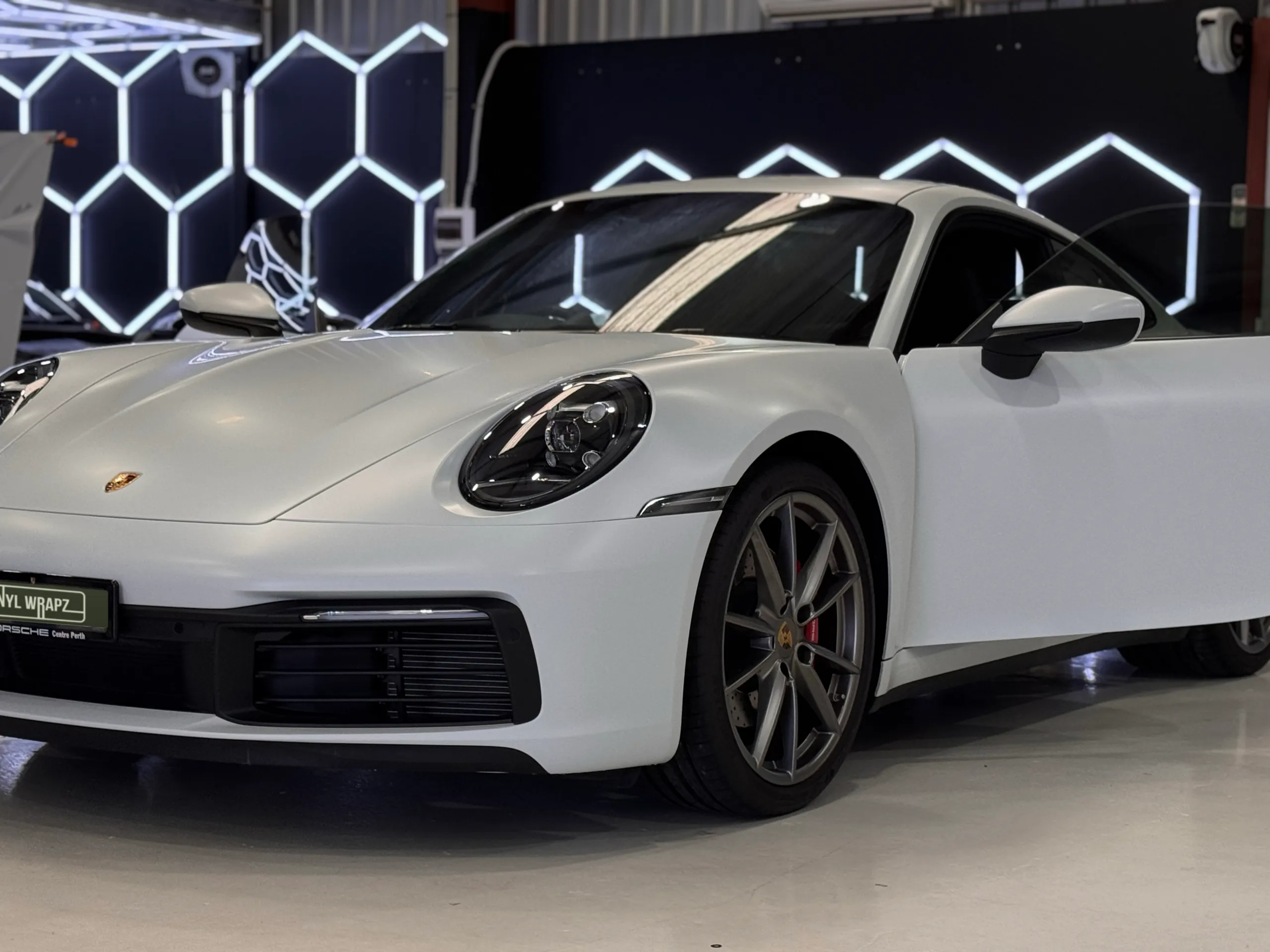 White Porsche 911 front quarter in the workshop with a door open