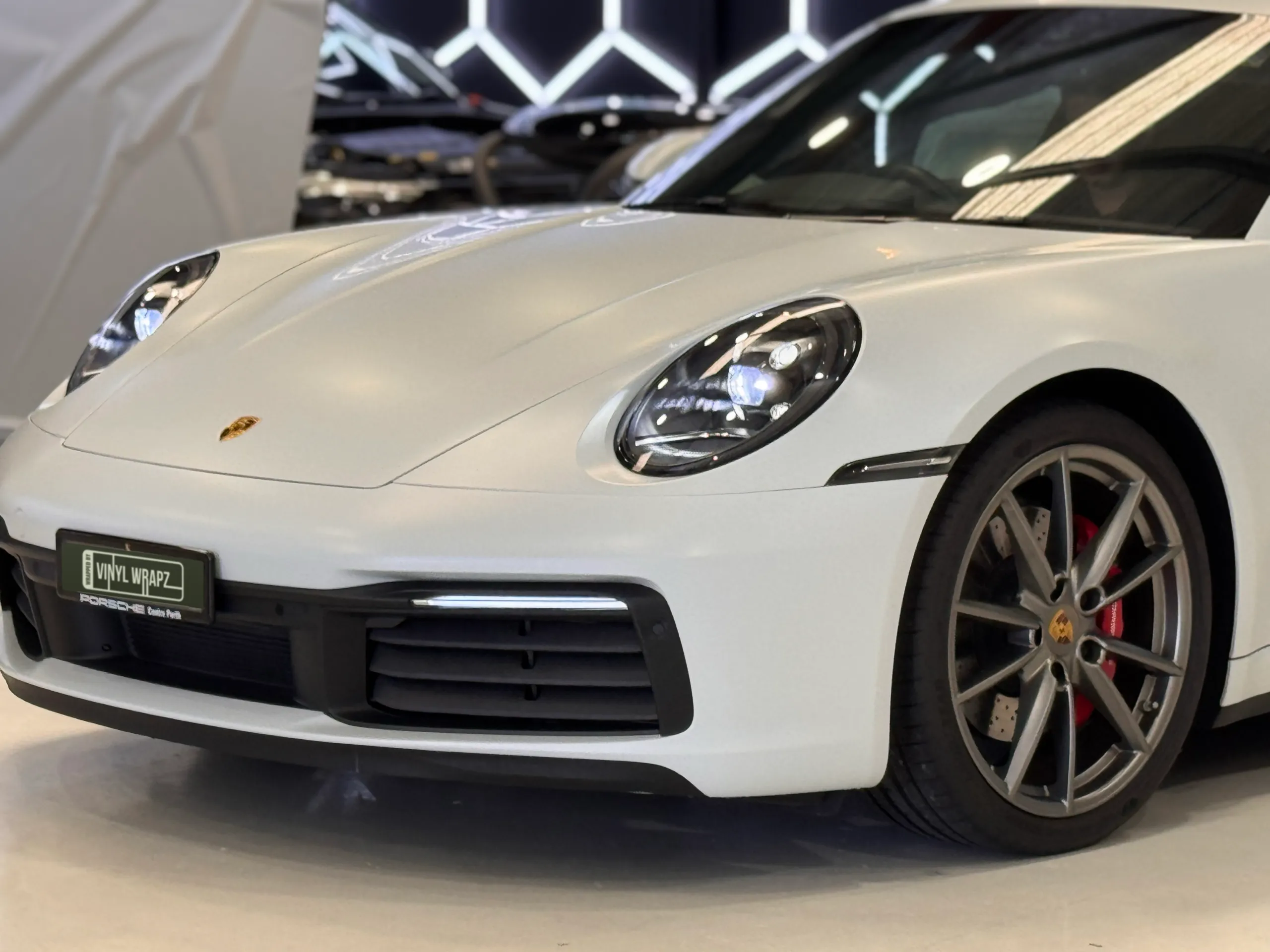 White Porsche 911 front bodywork, headlight and wheel in the workshop