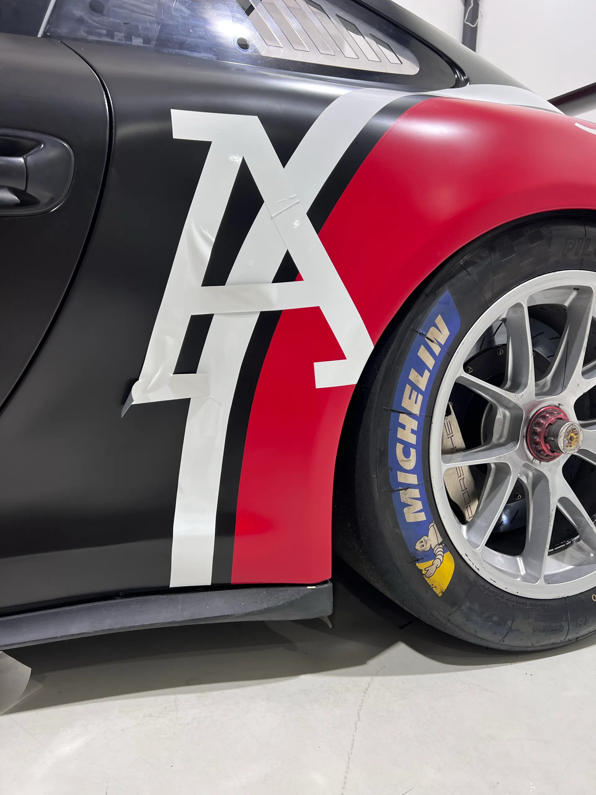 White lettering across the Porsche 911 black door and red rear quarter during livery fitting
