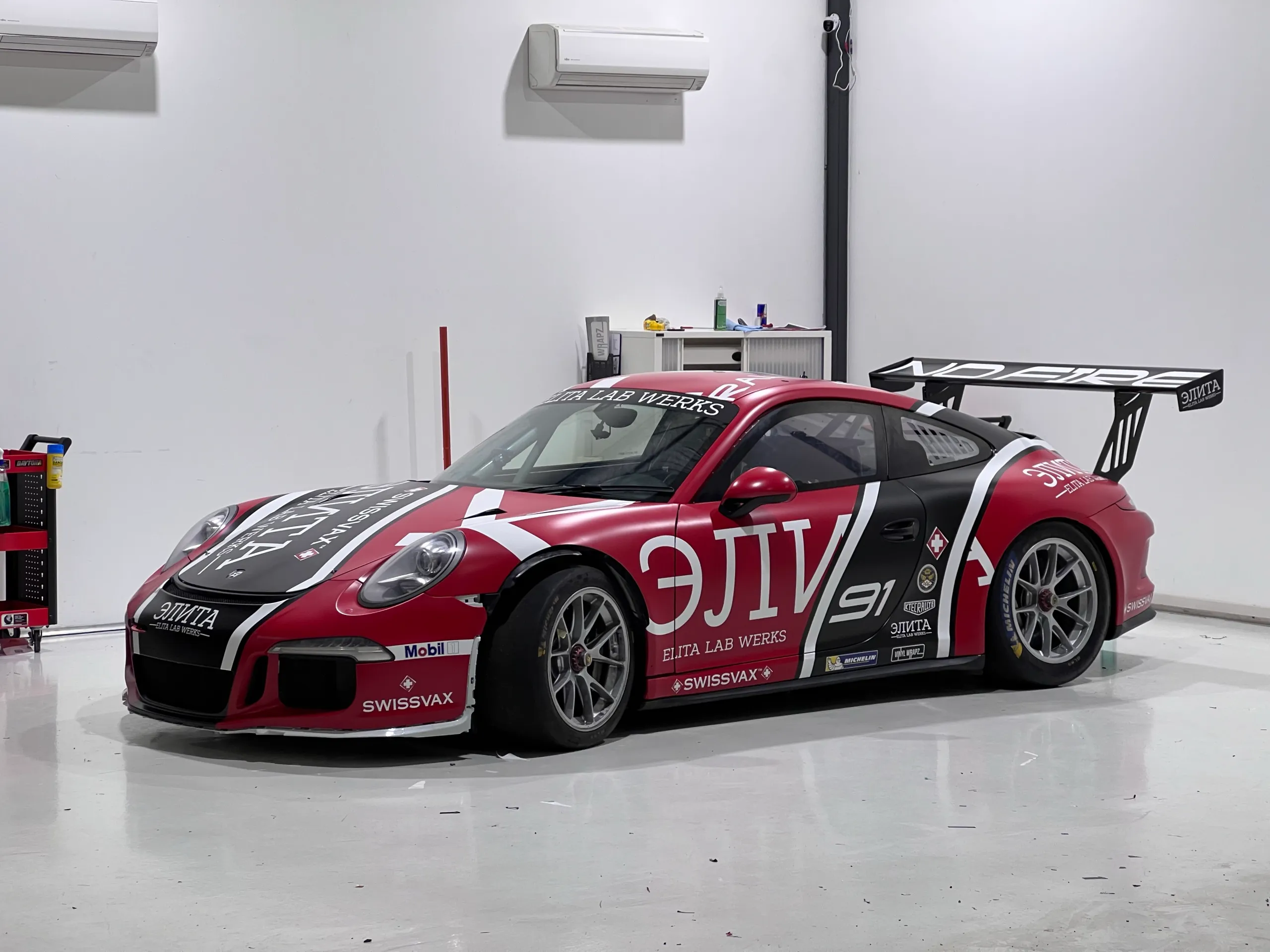 Elita Lab Werks Porsche 911 race car with red, black and white graphics in the workshop