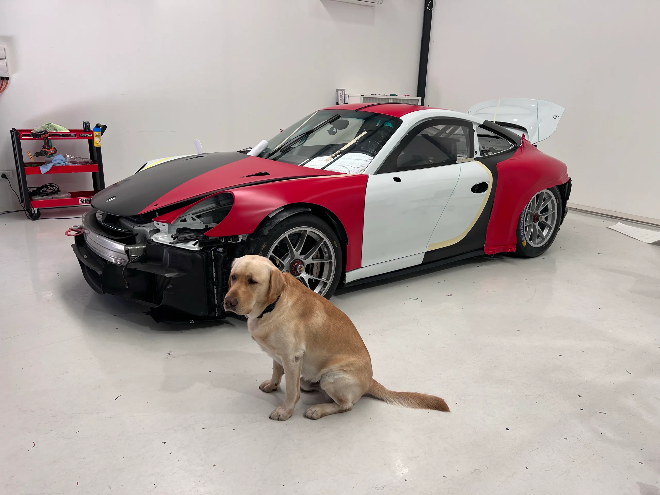 Workshop dog beside the Porsche during wrap installation