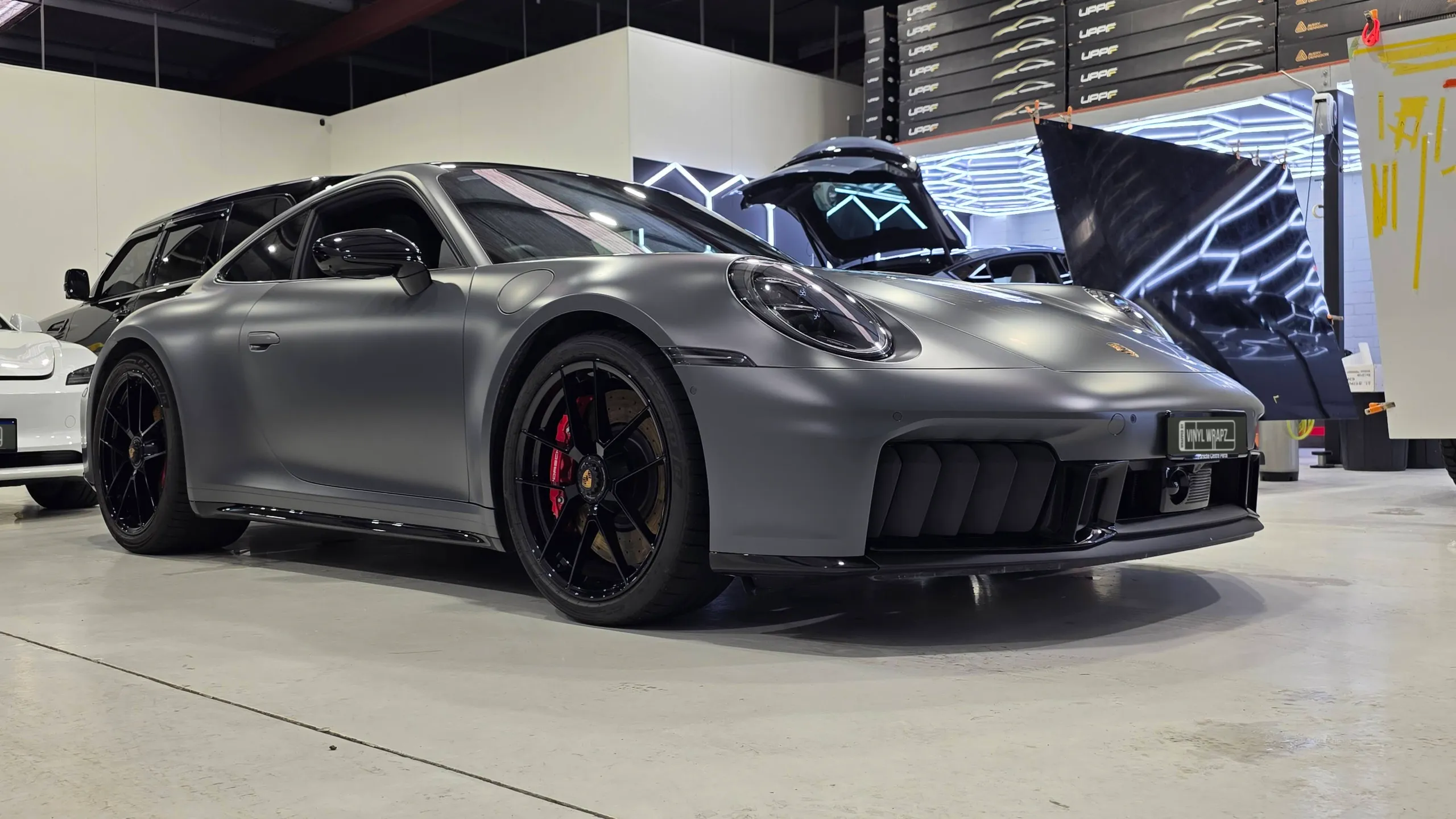 Satin grey Porsche 911 Carrera GTS with black wheels and red brake calipers in the workshop