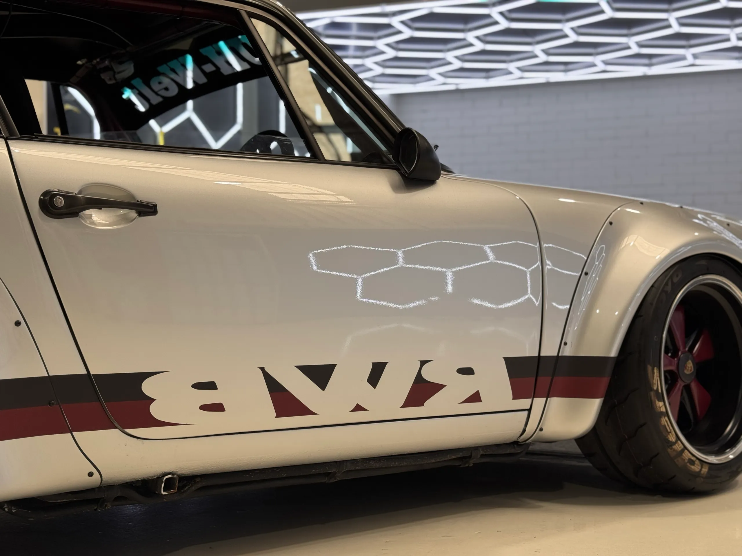 Close side view of white Porsche bodywork with black and red RWB graphics