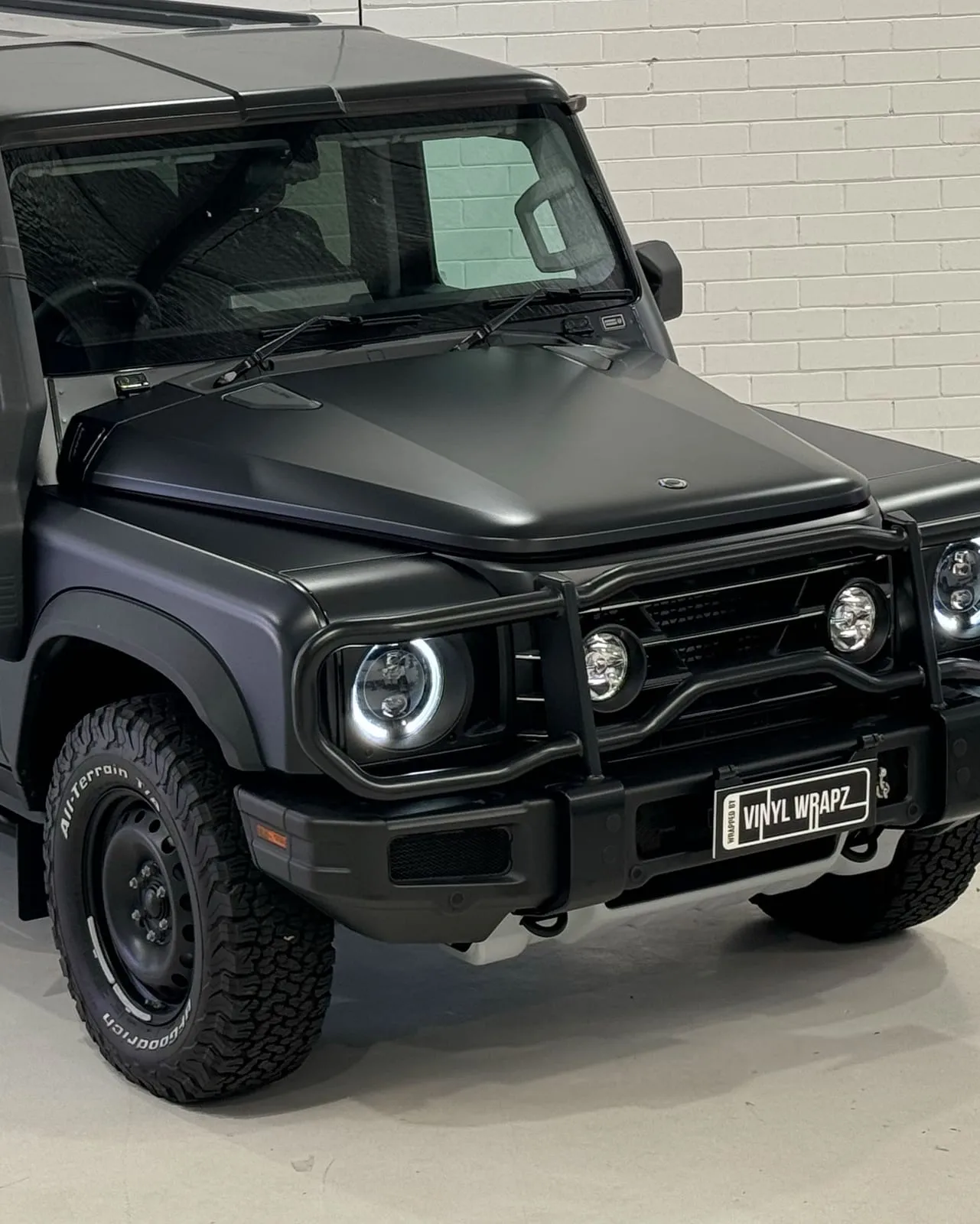 Matte paint protection film on the bonnet, front fender and headlight of an Ineos Grenadier, the film running to the panel edges