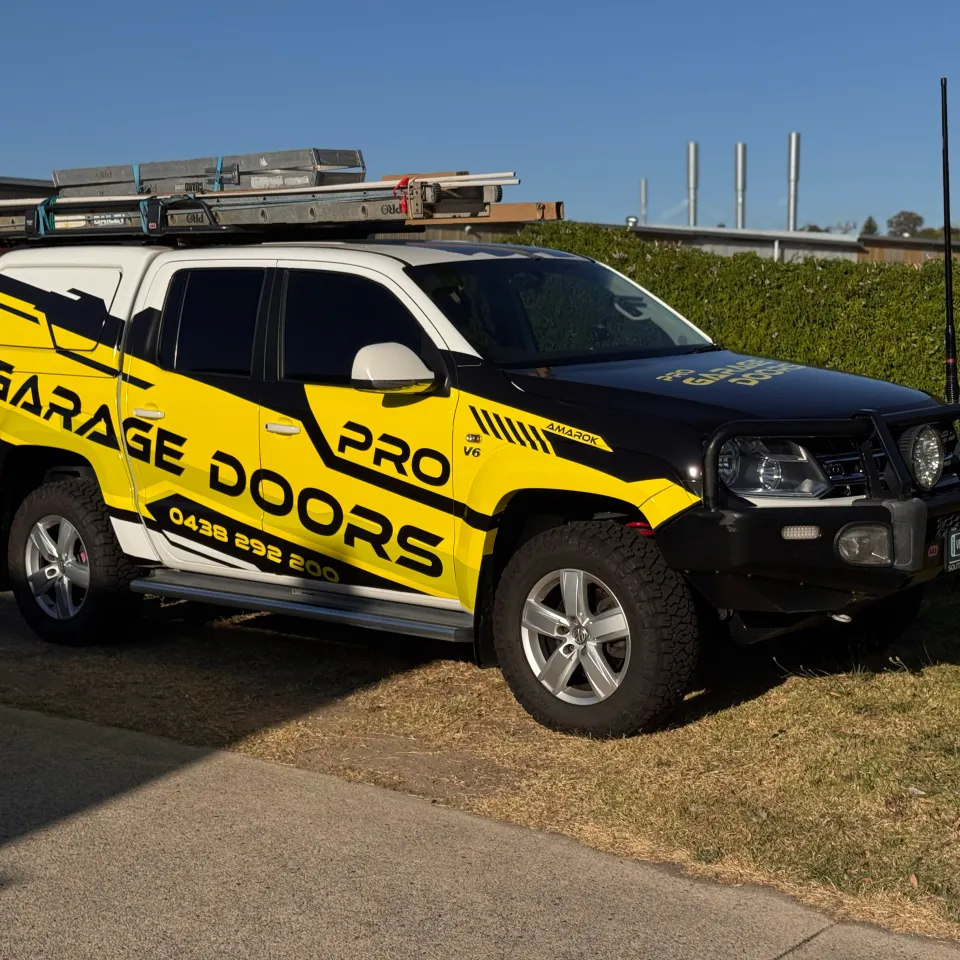 Volkswagen Amarok with yellow and black Pro Garage Doors graphics, parked on grass