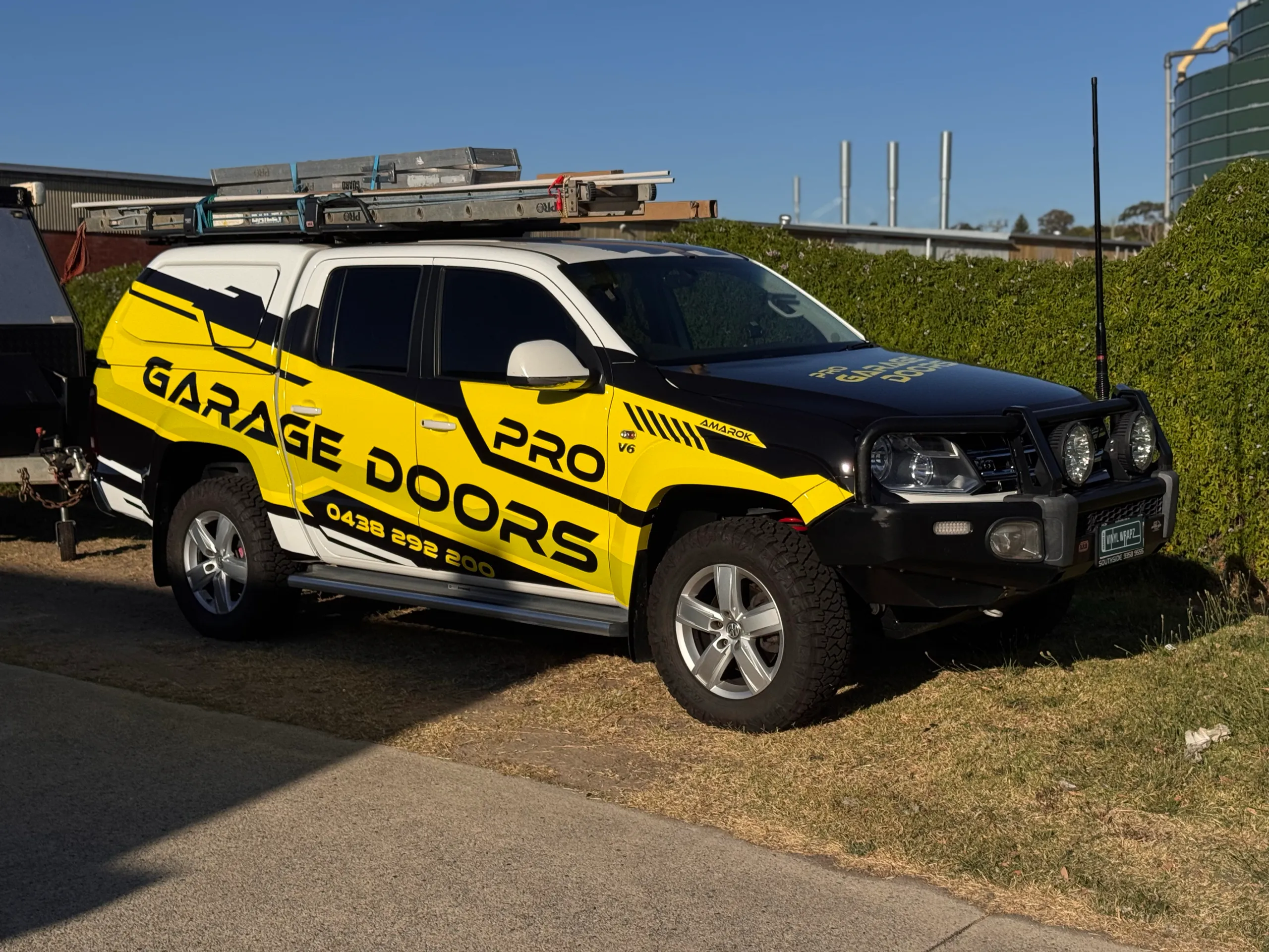 Volkswagen Amarok with yellow and black Pro Garage Doors graphics, parked on grass
