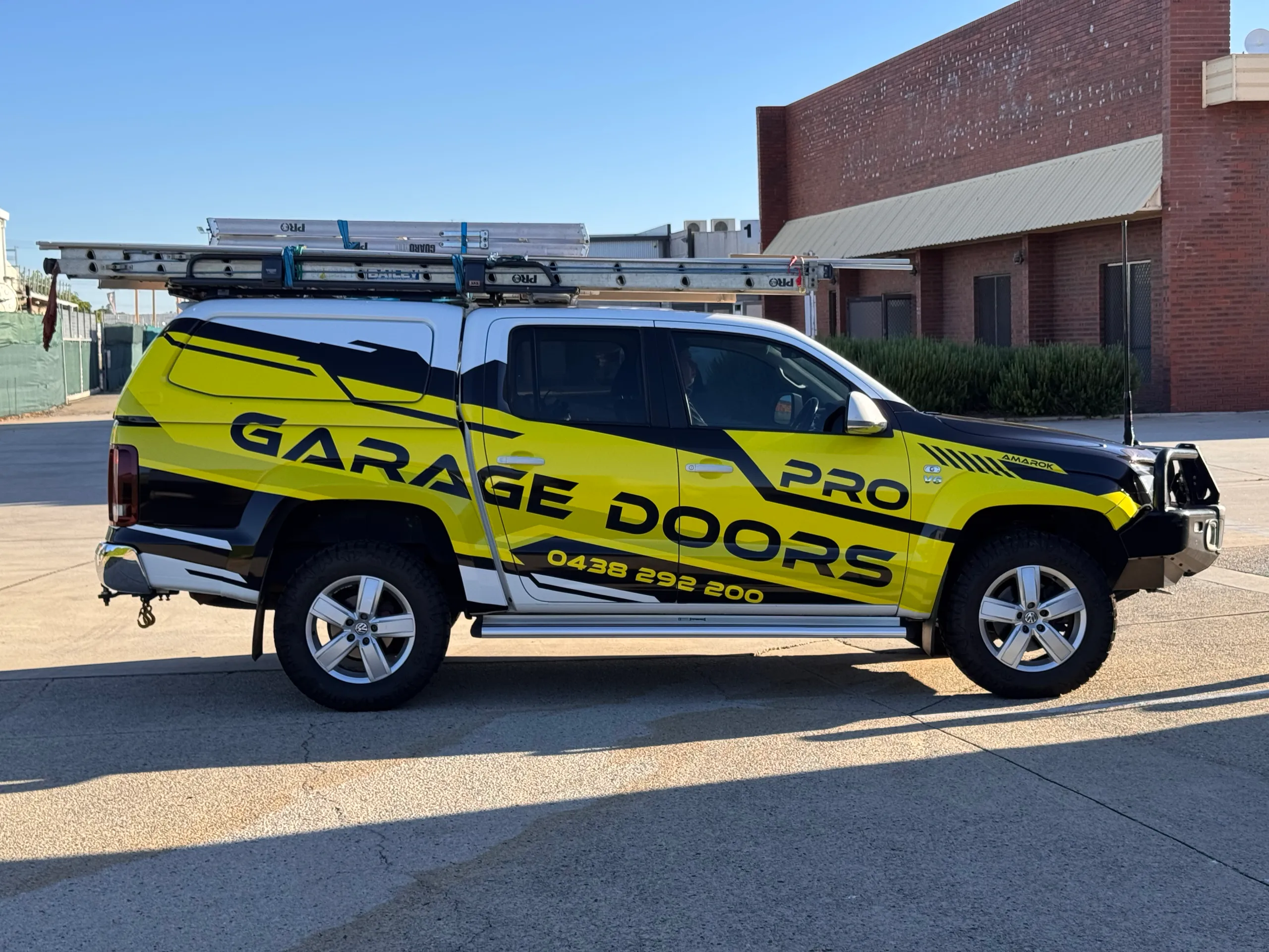 Side profile of the Volkswagen Amarok with Pro Garage Doors graphics and a ladder rack