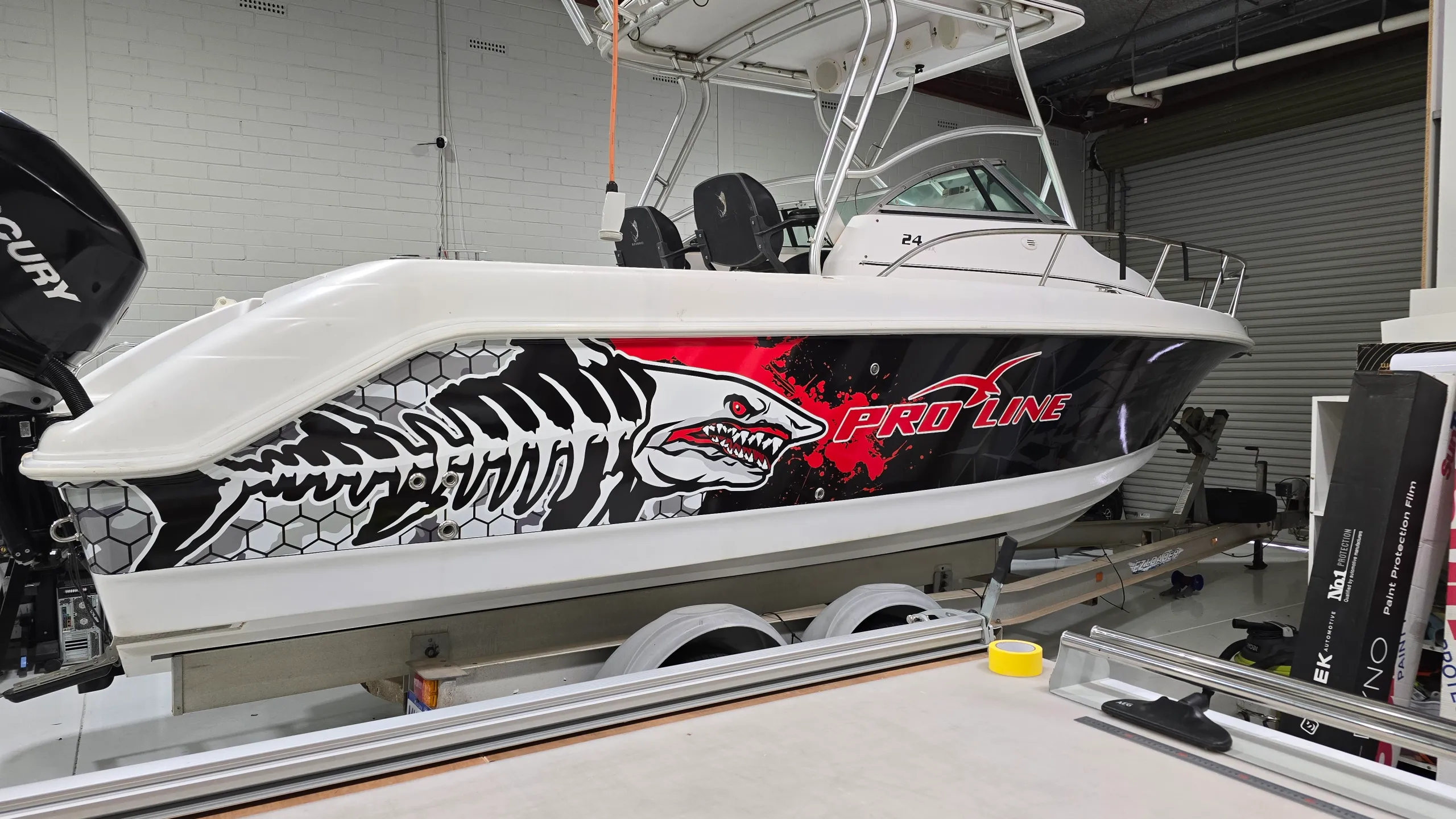 Black, red and white shark graphics along the Pro-Line boat hull in the workshop