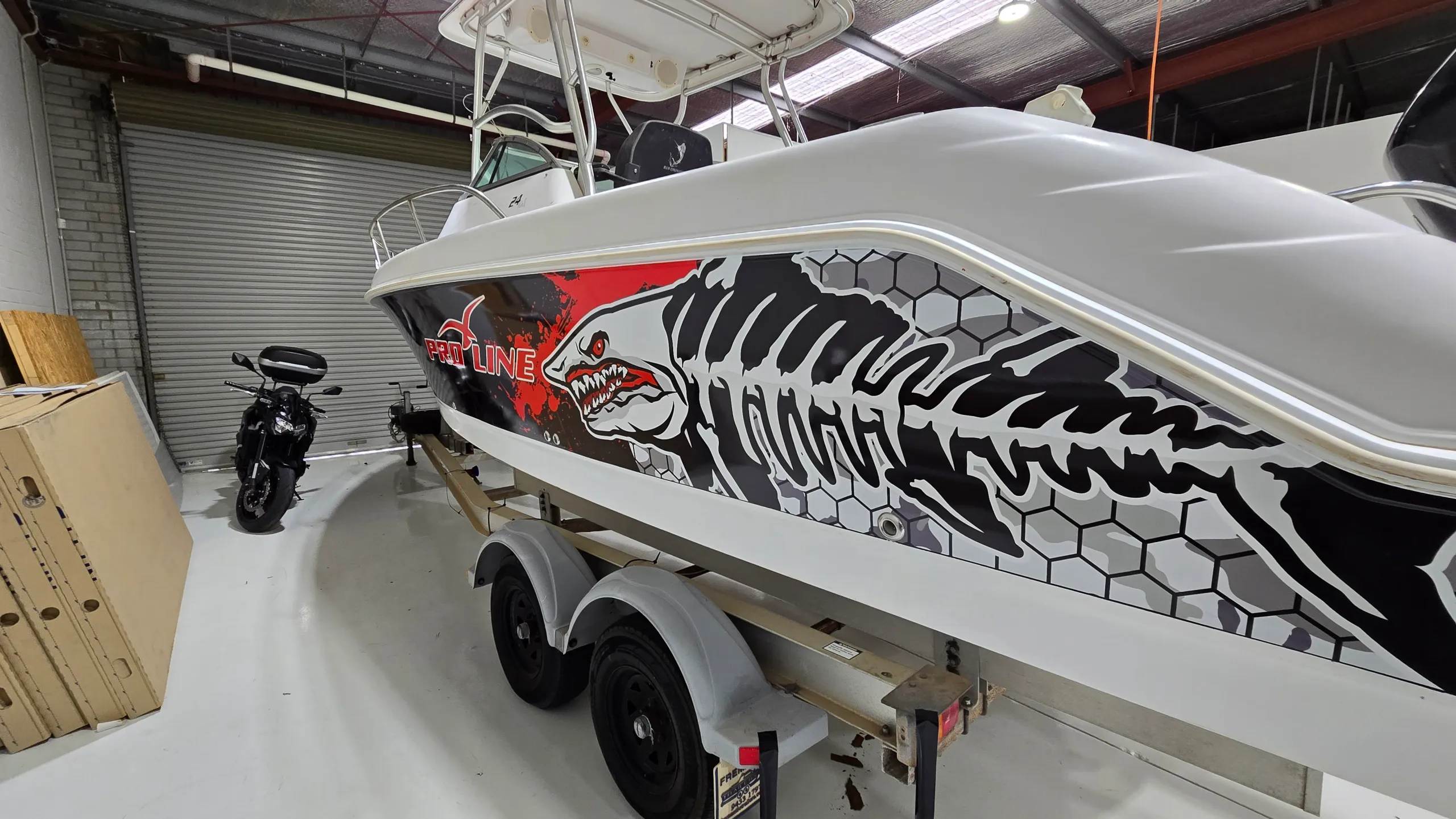 White shark skeleton artwork across the Pro-Line boat hull above its trailer wheels