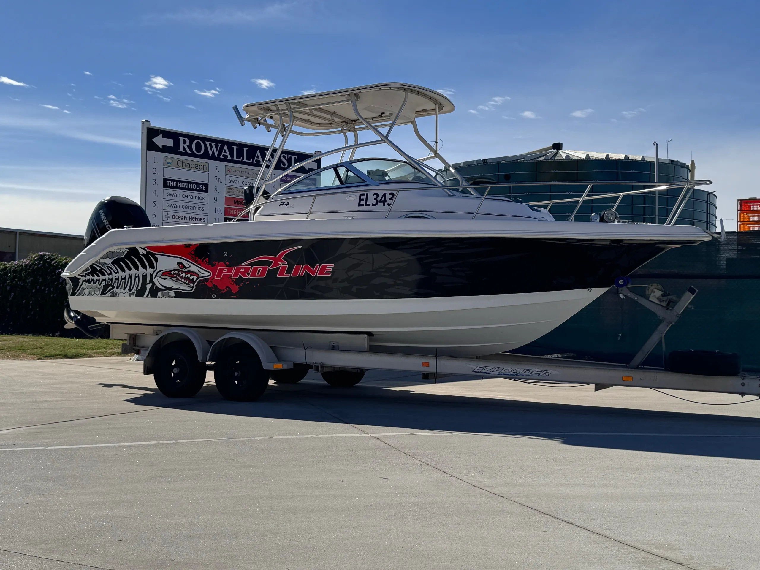 Pro-Line boat with black, red and white shark graphics on its trailer outdoors