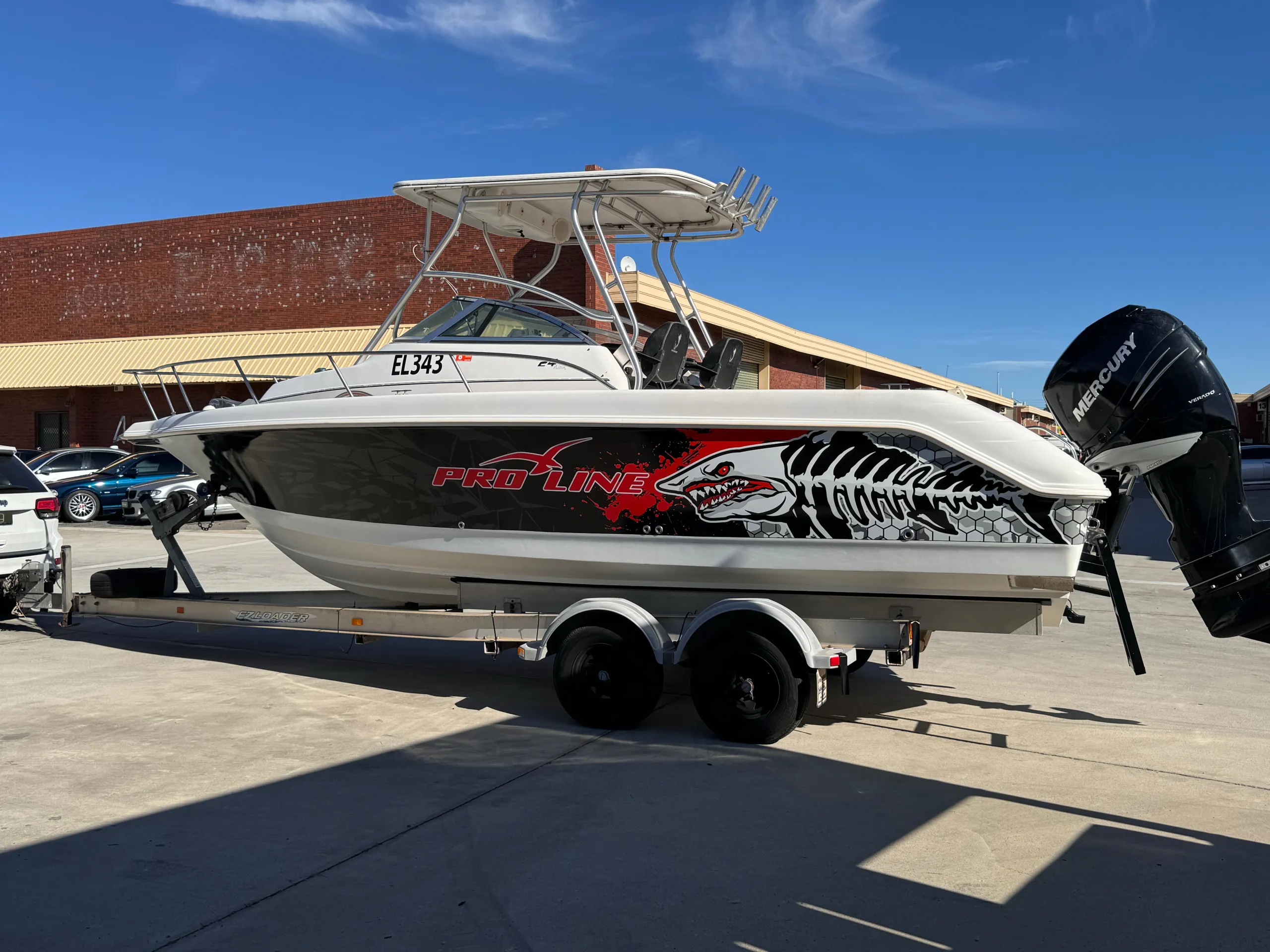Side view of the Pro-Line boat showing red lettering and white shark skeleton graphics outdoors