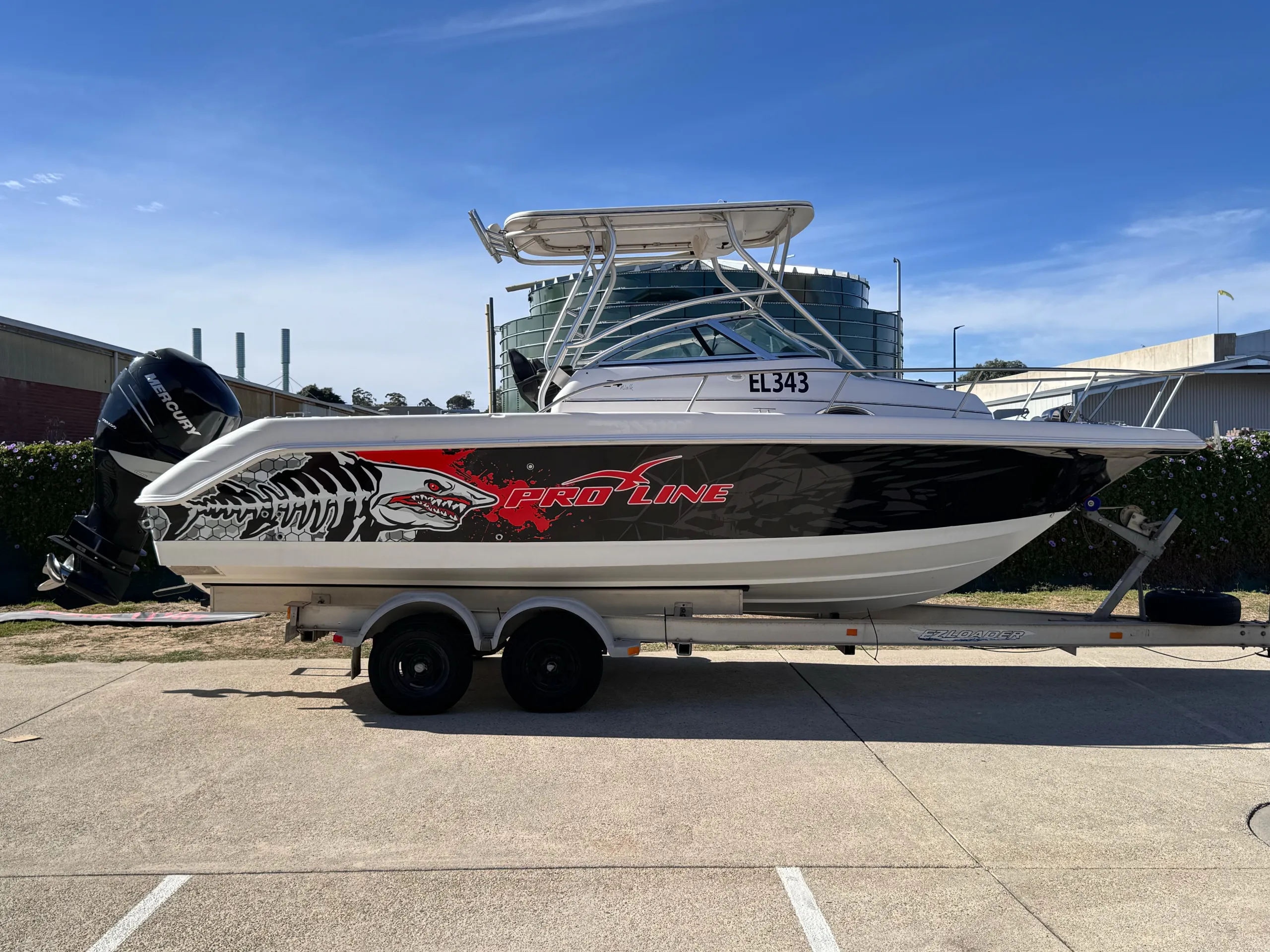 Pro-Line boat on a trailer with a black hull wrap, red lettering and white shark artwork