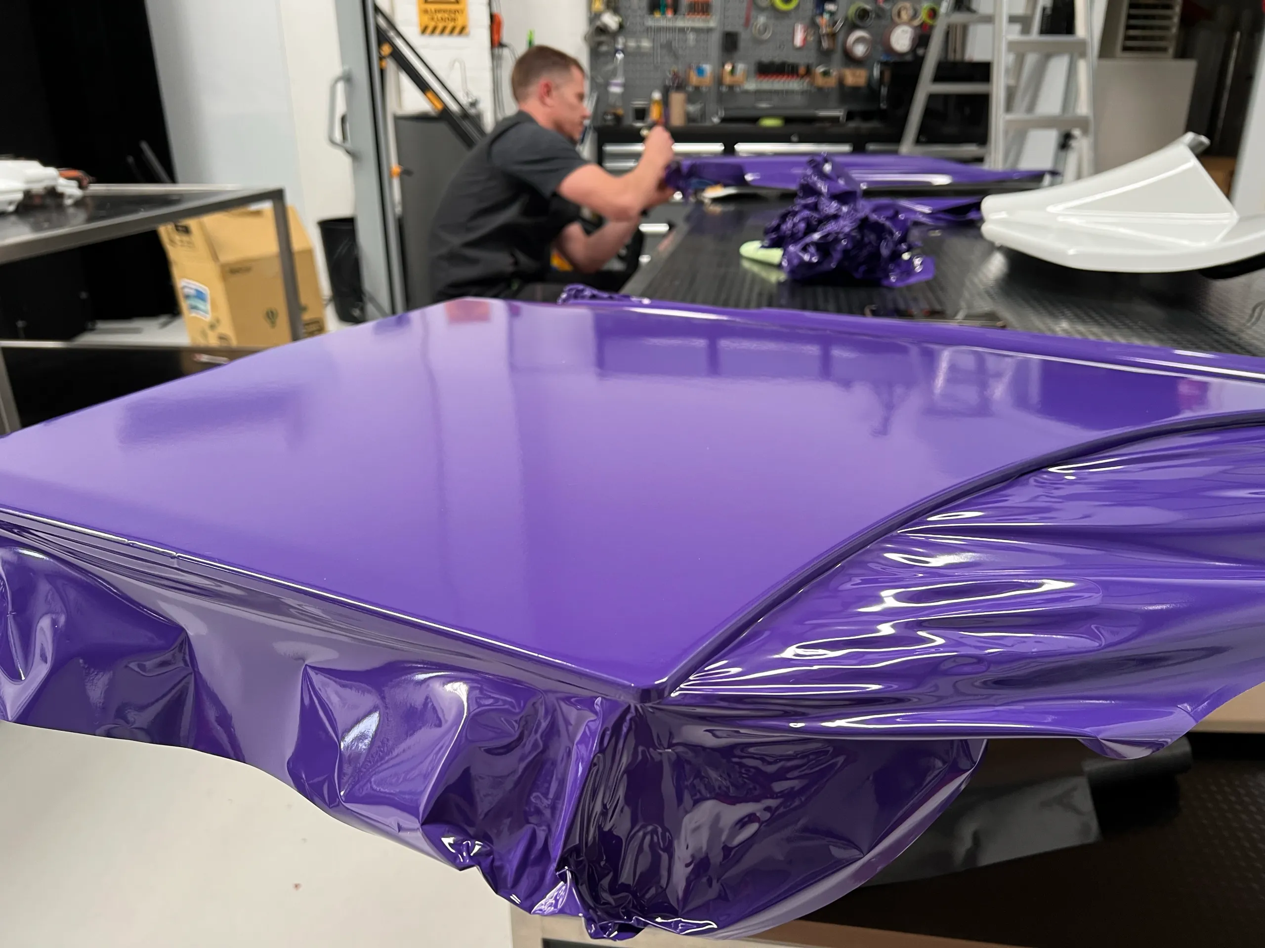 Installer finishing a purple cab panel on the workshop bench