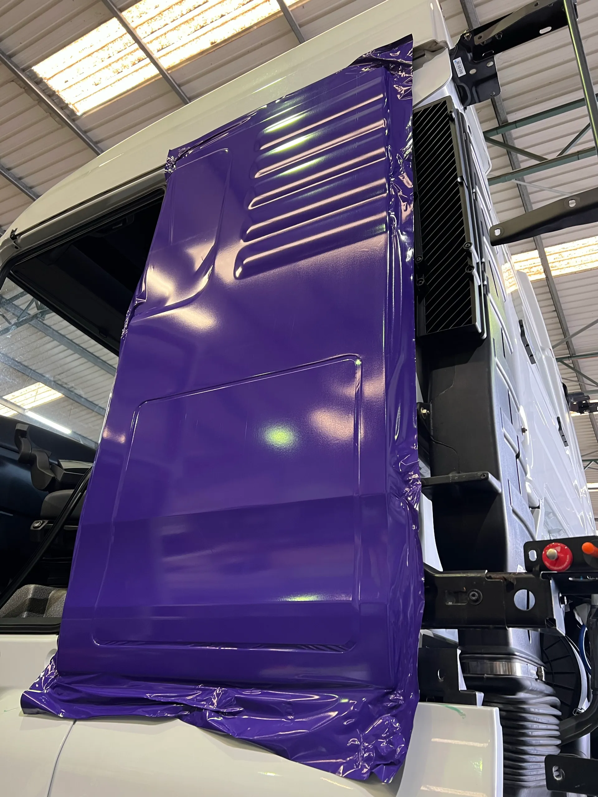 Purple film being fitted to a detached truck door