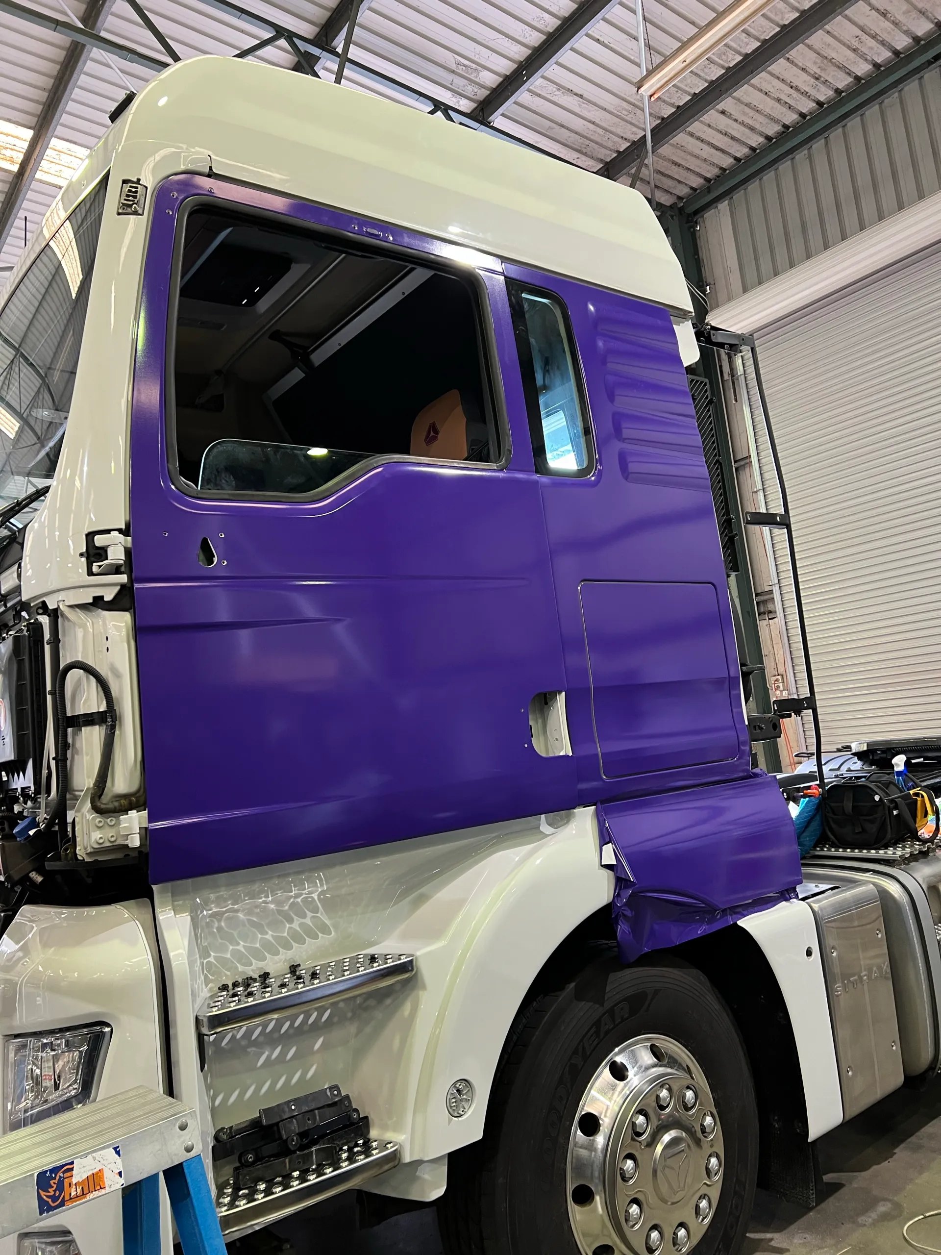Purple truck door reassembled with its handles and trim