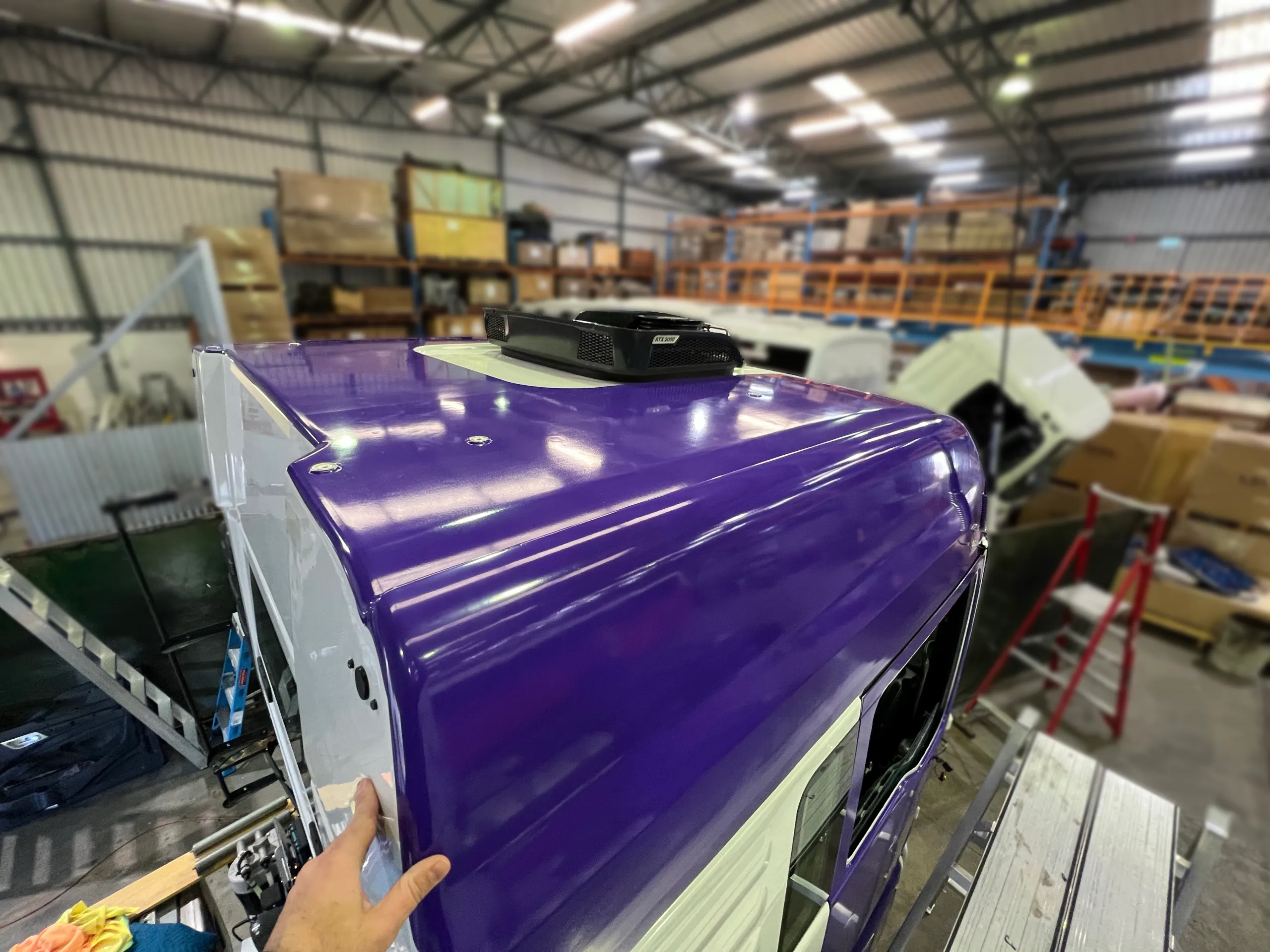 Hand working purple film over a detached roof panel