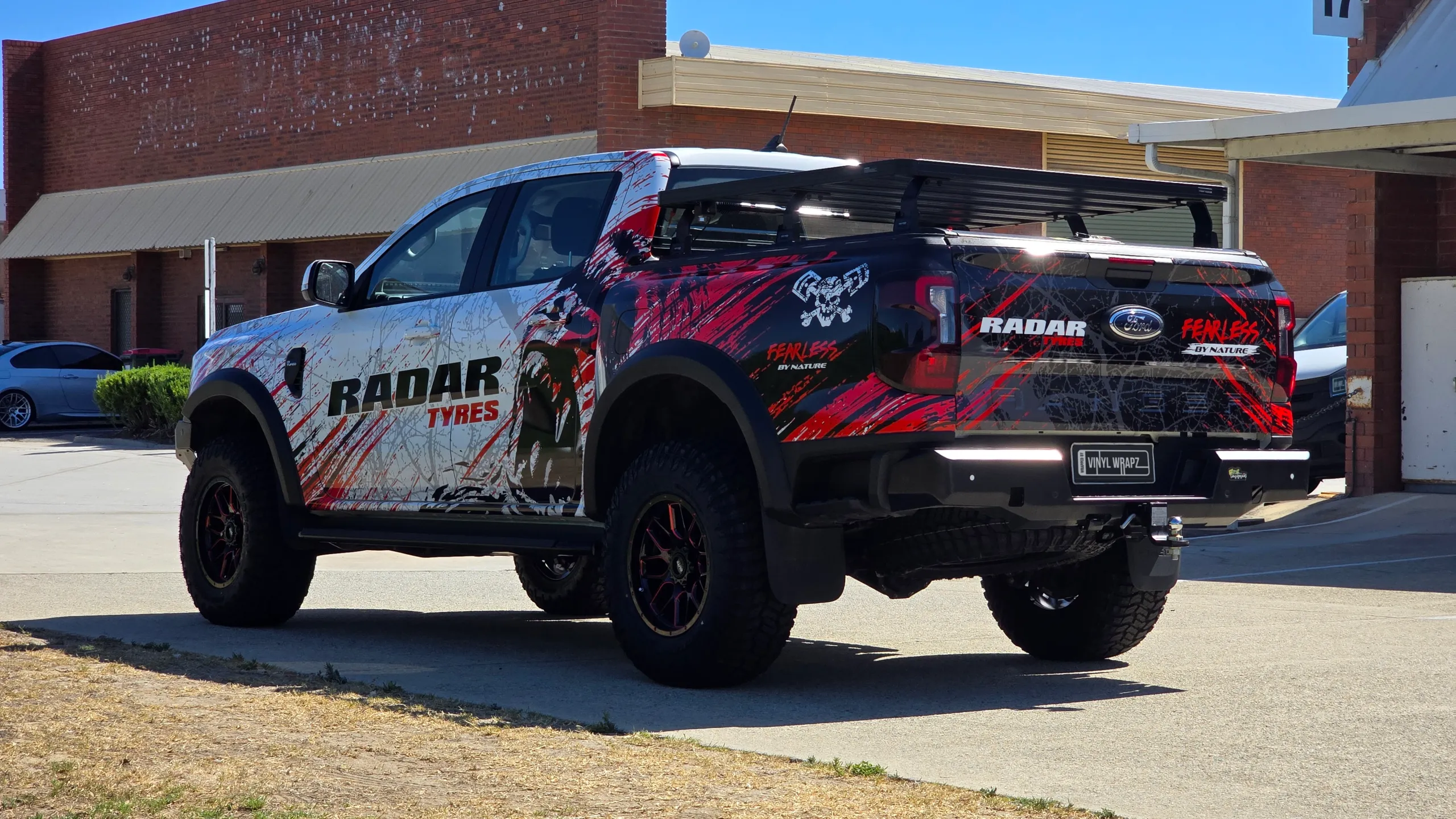 Rear-quarter view of the red, black and white Radar Tyres Ford Ranger outdoors