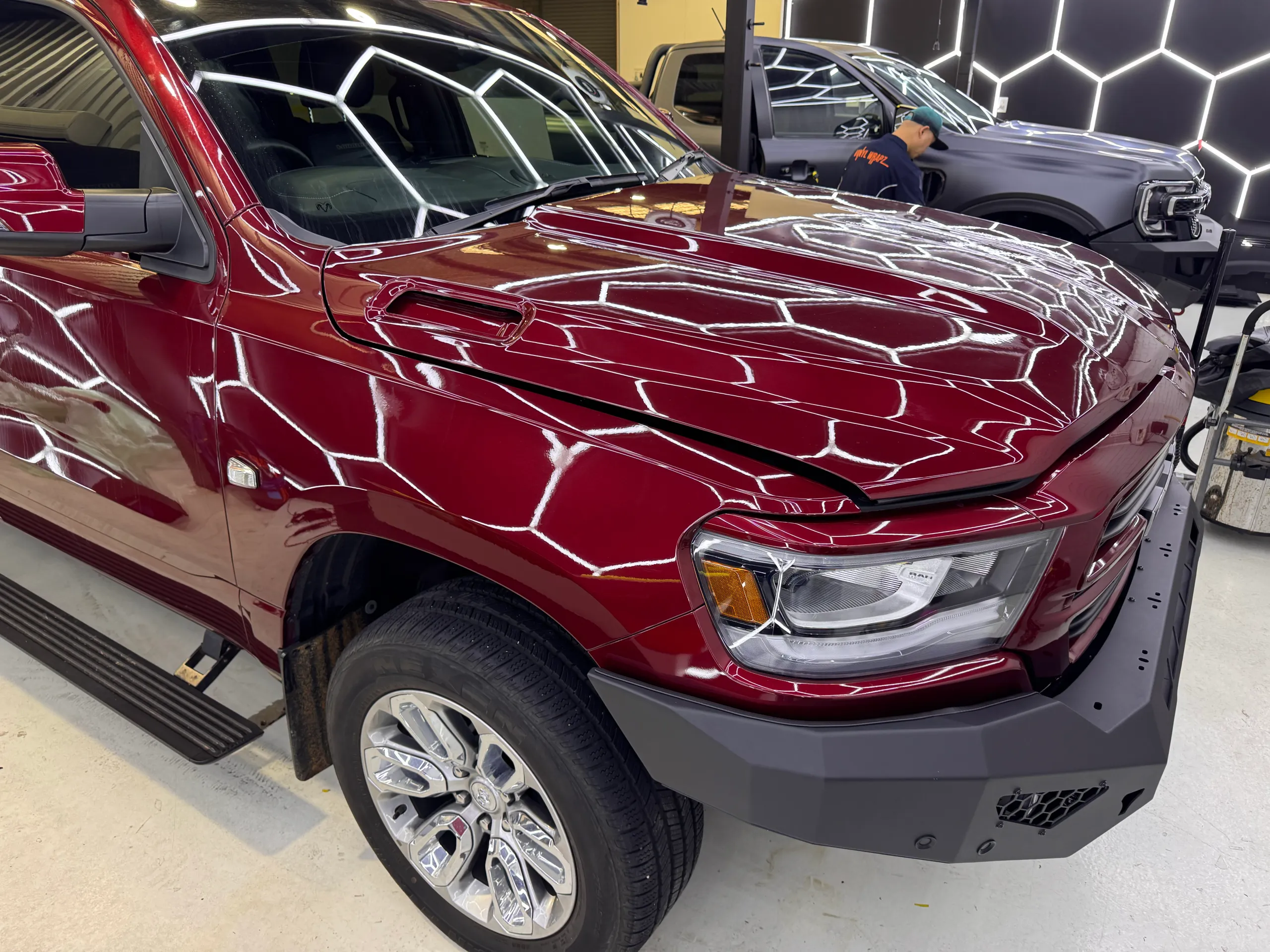 Front quarter of a dark red Ram 1500 in the workshop with its bonnet slightly raised