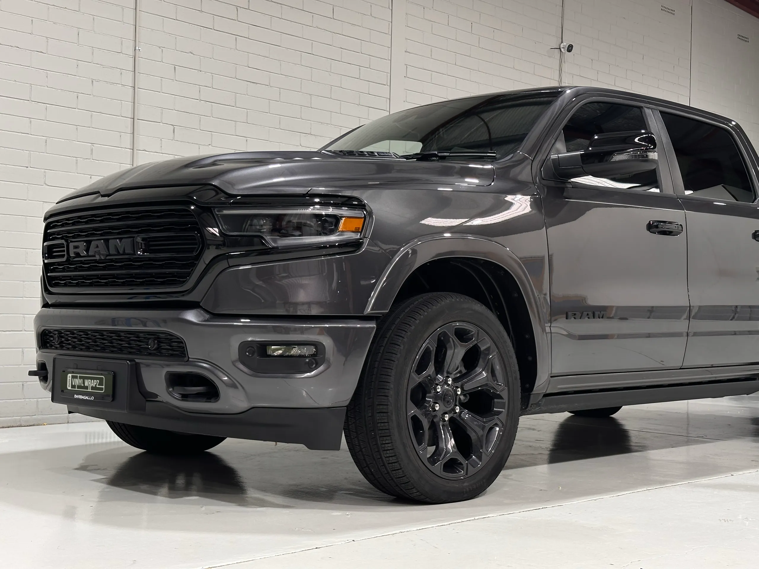 Low front-quarter view of the grey Ram 1500 grille, front wheel and cab