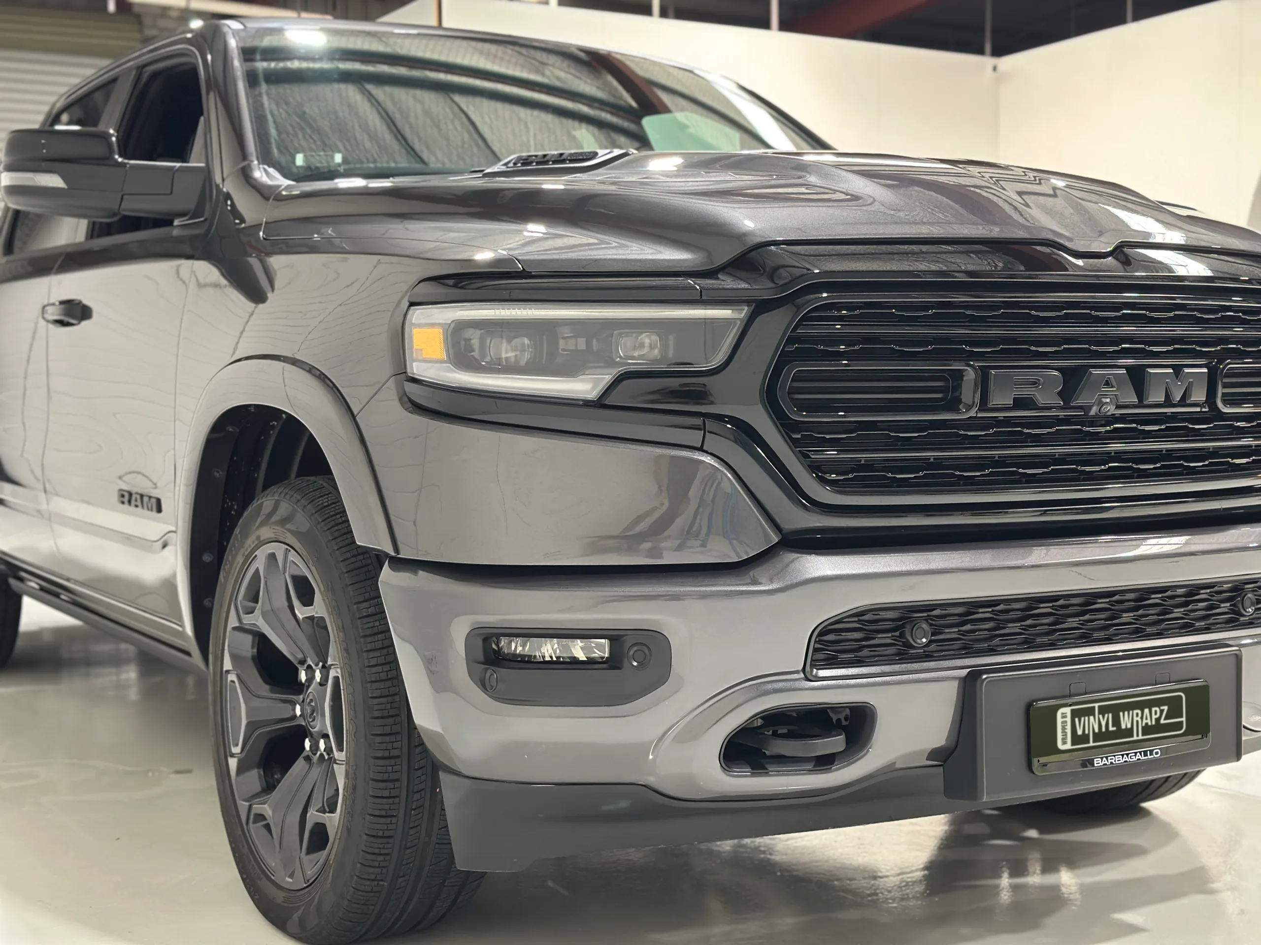 Close front-quarter view of the grey Ram 1500 grille and headlight
