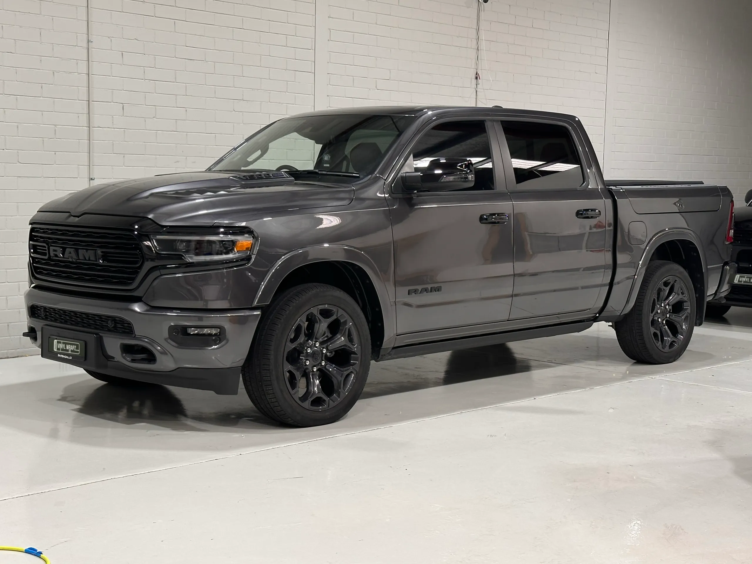 Metallic grey Ram 1500 viewed from the front quarter against the workshop wall