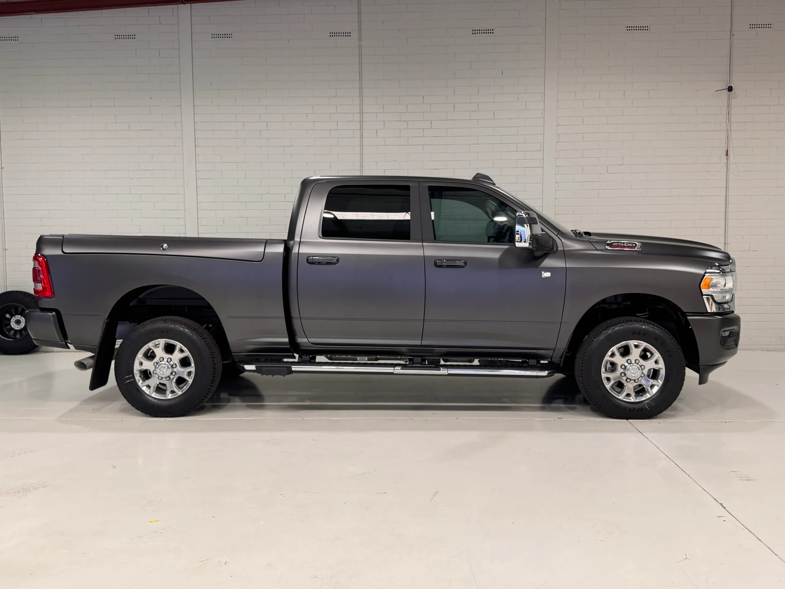 Full side profile of a matte grey Ram 2500 in the workshop