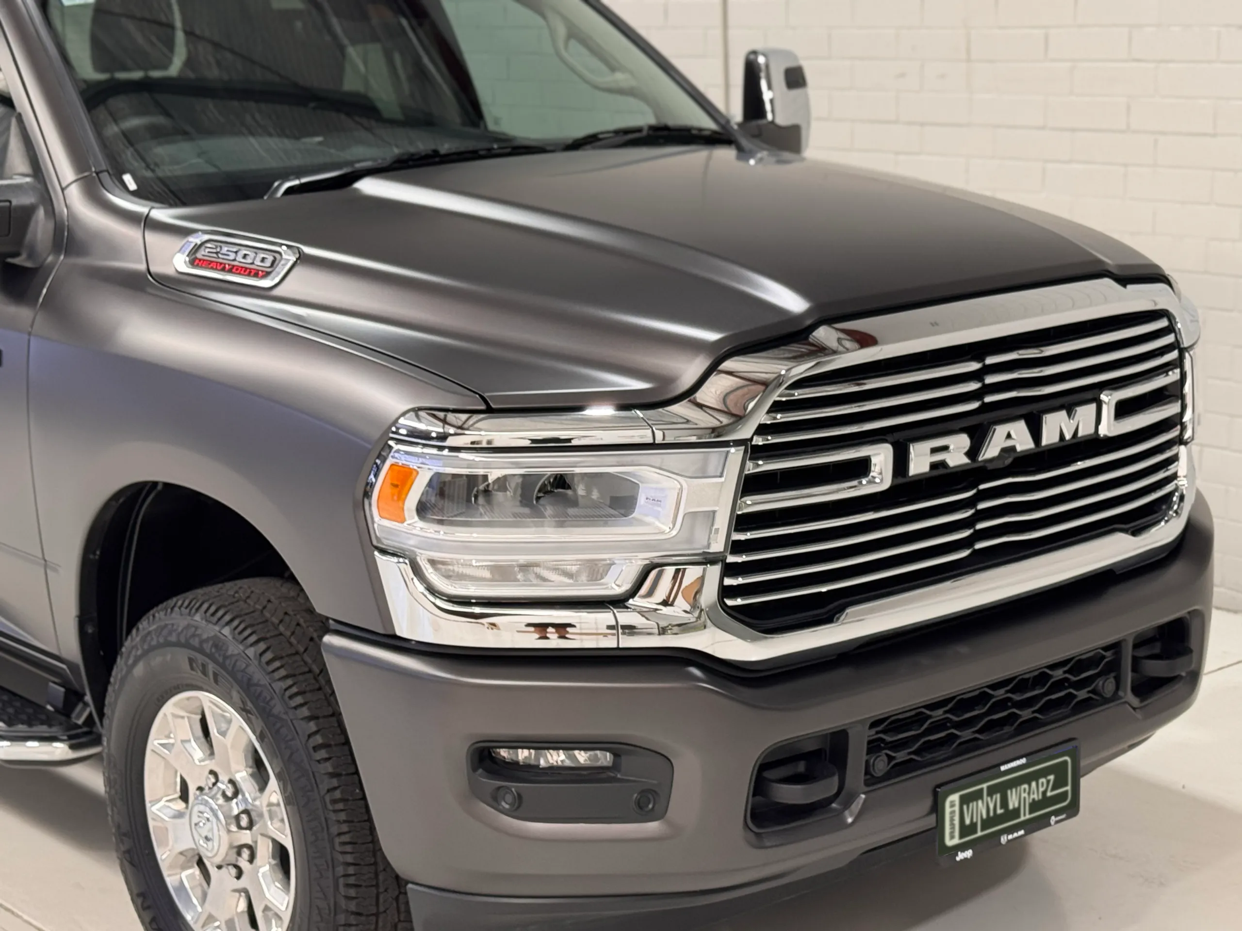 Chrome grille and headlight against the matte grey Ram 2500 bonnet