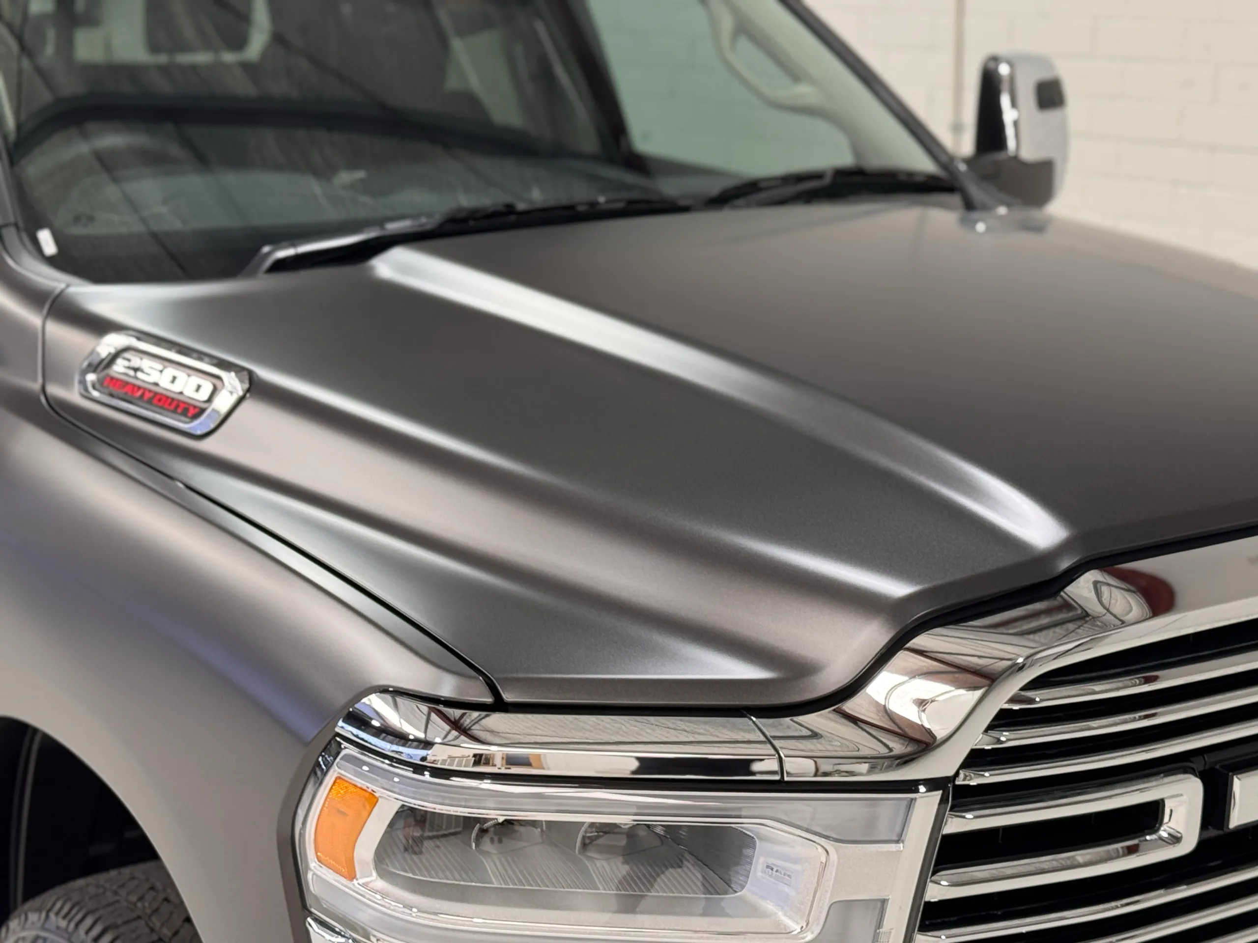 Close-up of the matte grey Ram 2500 bonnet, badge and headlight