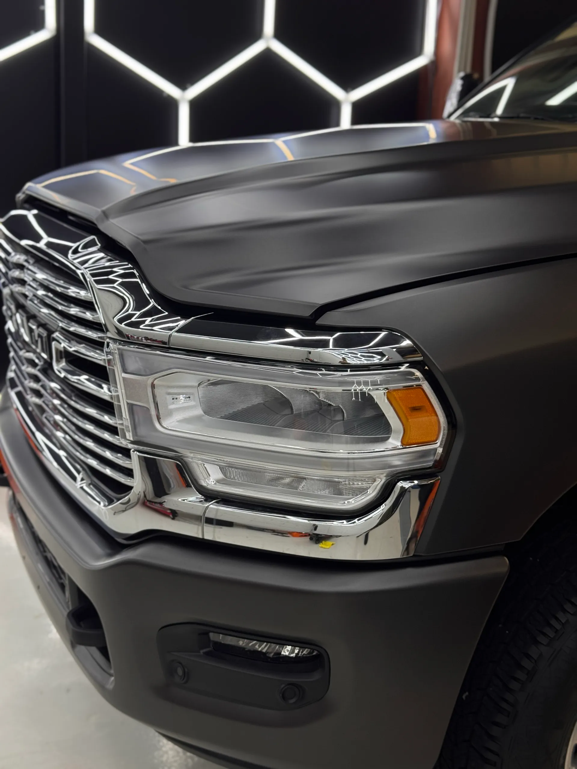 Ram 2500 headlight and chrome grille beside satin dark grey bodywork
