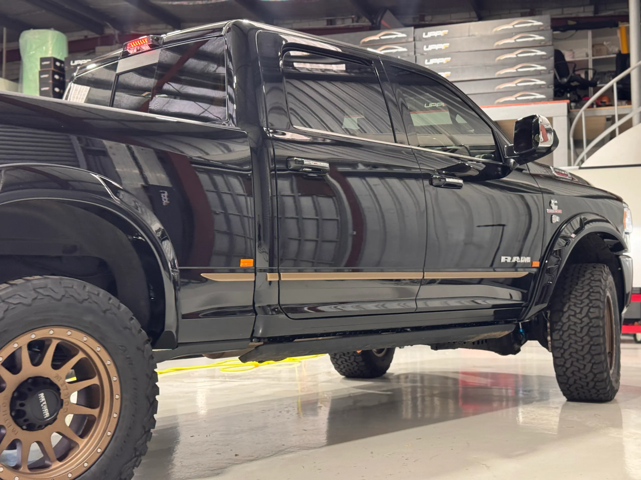 Gloss black Ram 3500 cab and bronze wheels inside the workshop