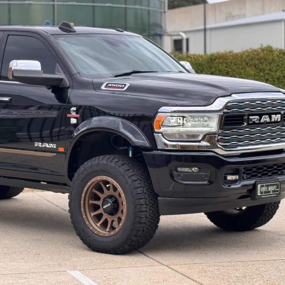 Closer front-quarter view of the black Ram 3500 cab and bronze front wheel