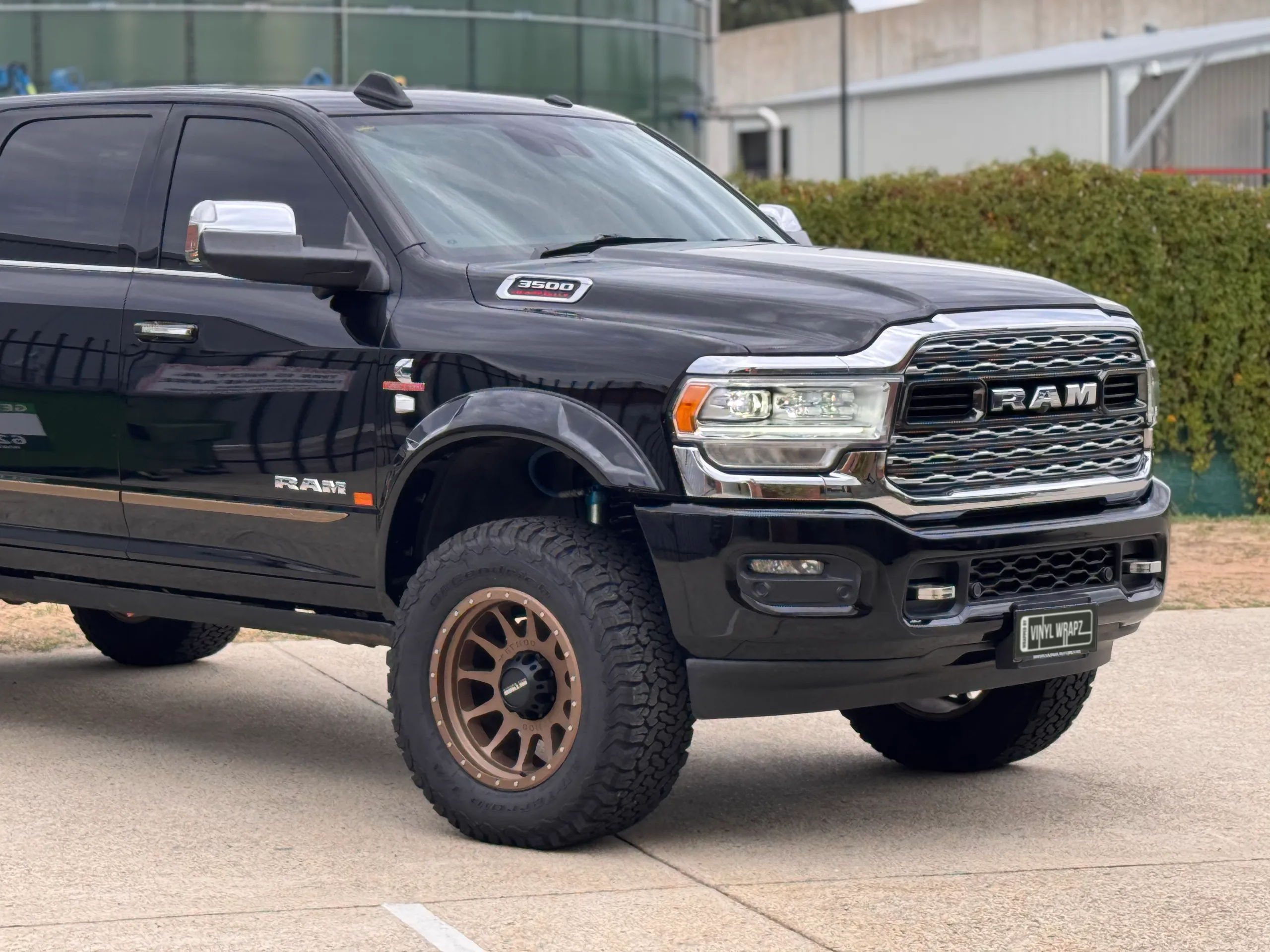 Closer front-quarter view of the black Ram 3500 cab and bronze front wheel