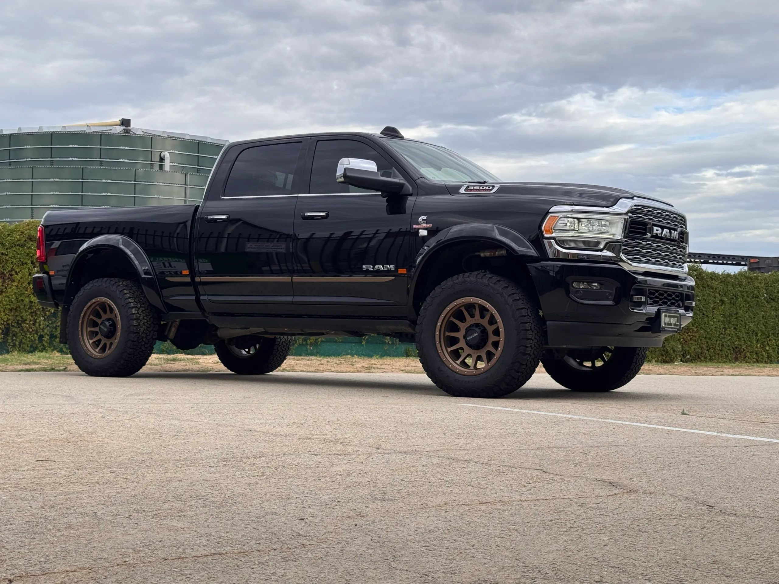 Low side-quarter view of the black Ram 3500 beneath an overcast sky