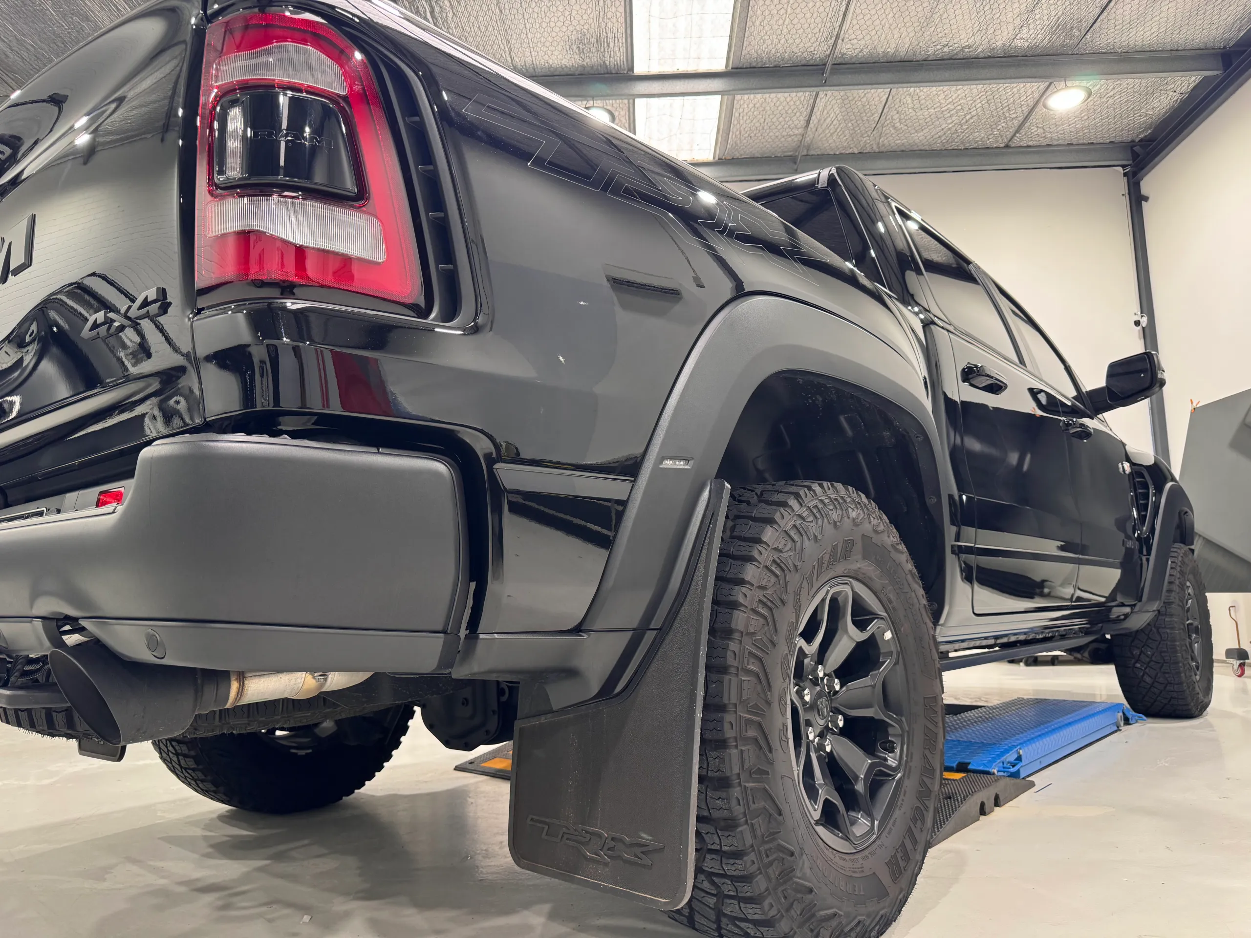 Low rear-quarter view of a gloss black Ram TRX, showing its rear wheel and mud flap