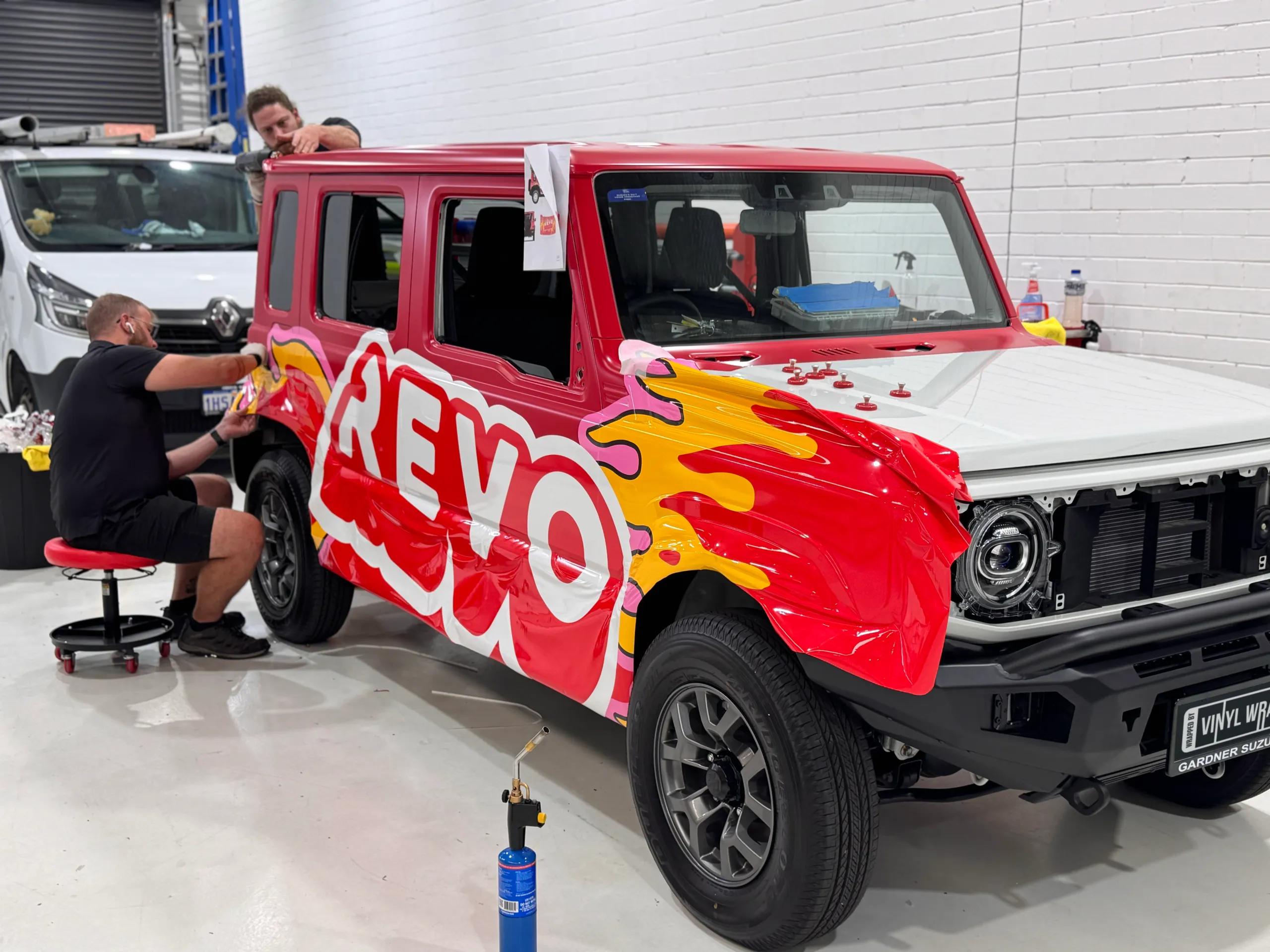 Red Revo graphics being fitted to the Jimny with front trim removed