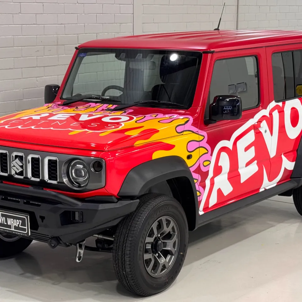 Red Suzuki Jimny with Revo Fitness bonnet branding and flame graphics in the workshop