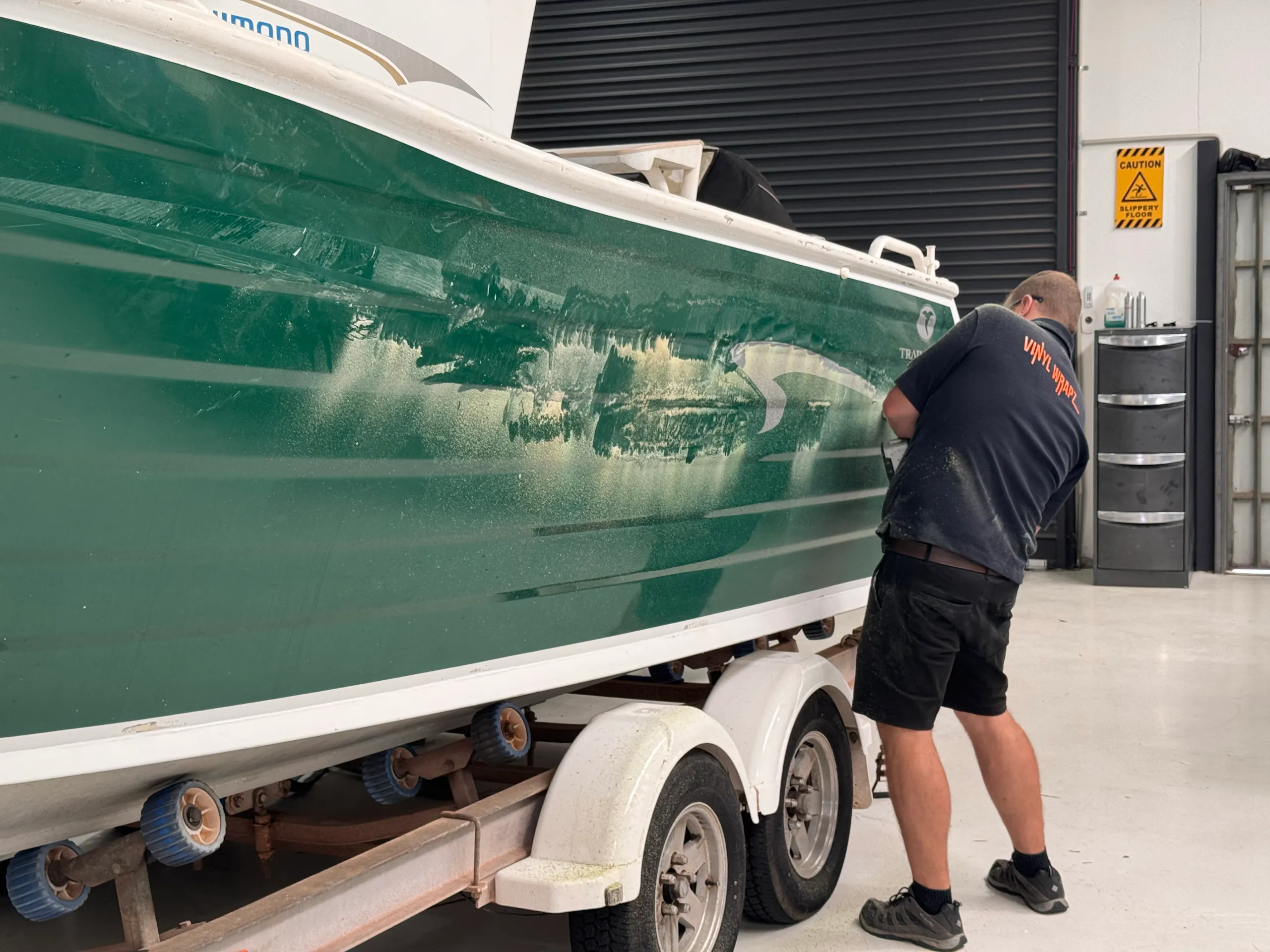 Close view of an installer preparing the green boat hull at the stern