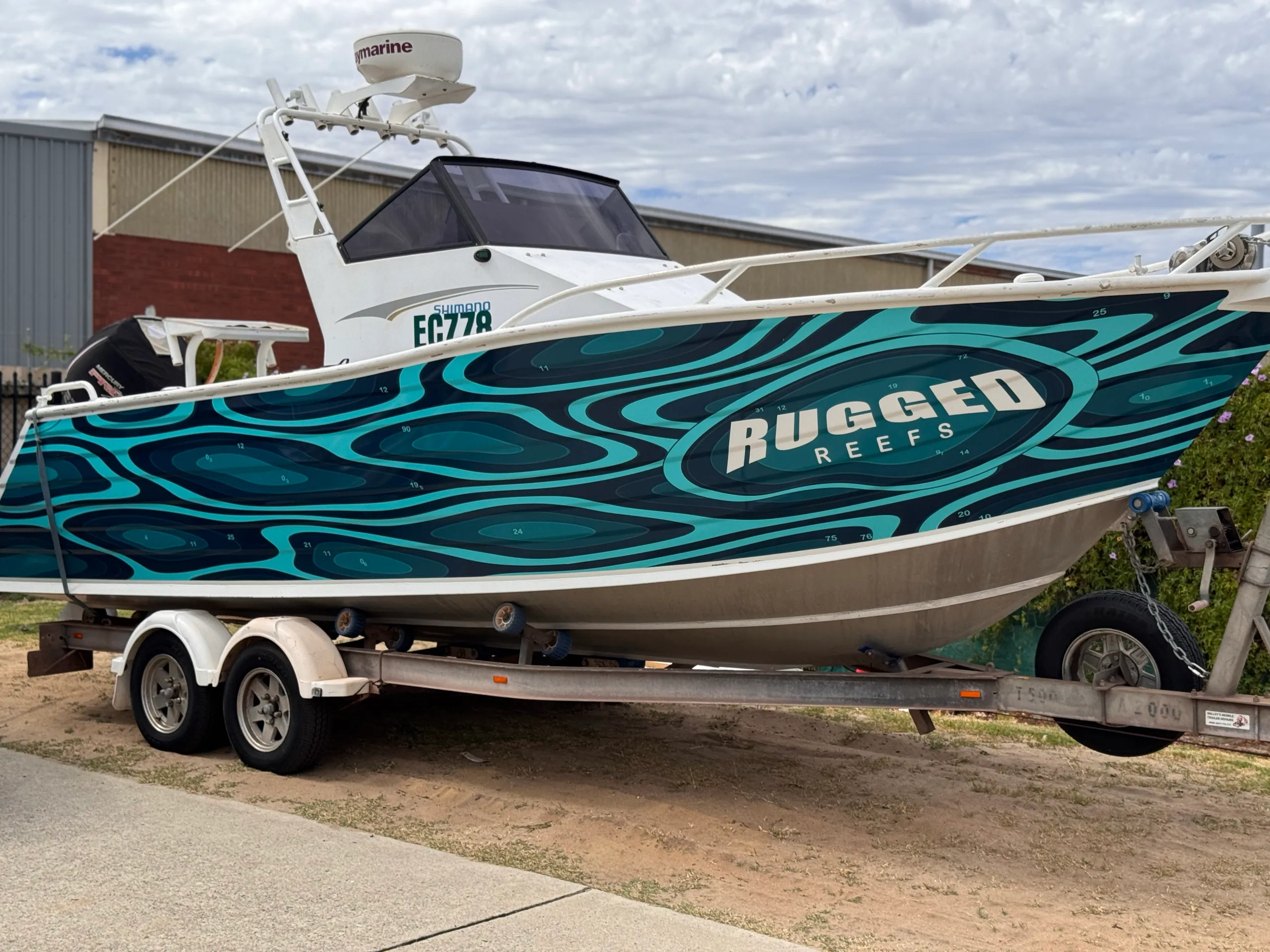 Closer view of the teal topographic graphics and Rugged Reefs lettering on the hull
