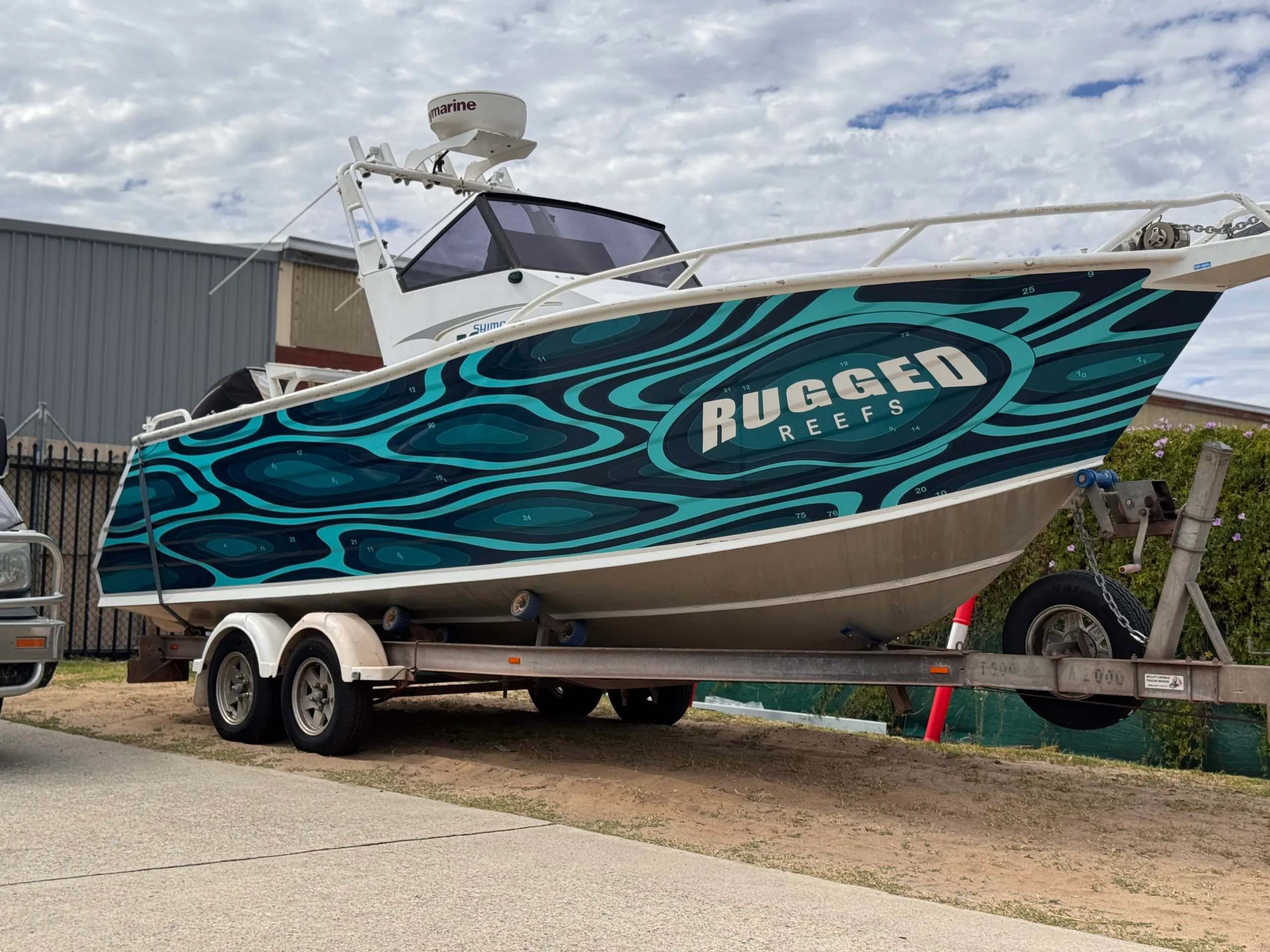 Side view of the Rugged Reefs hull graphics with the boat on its trailer
