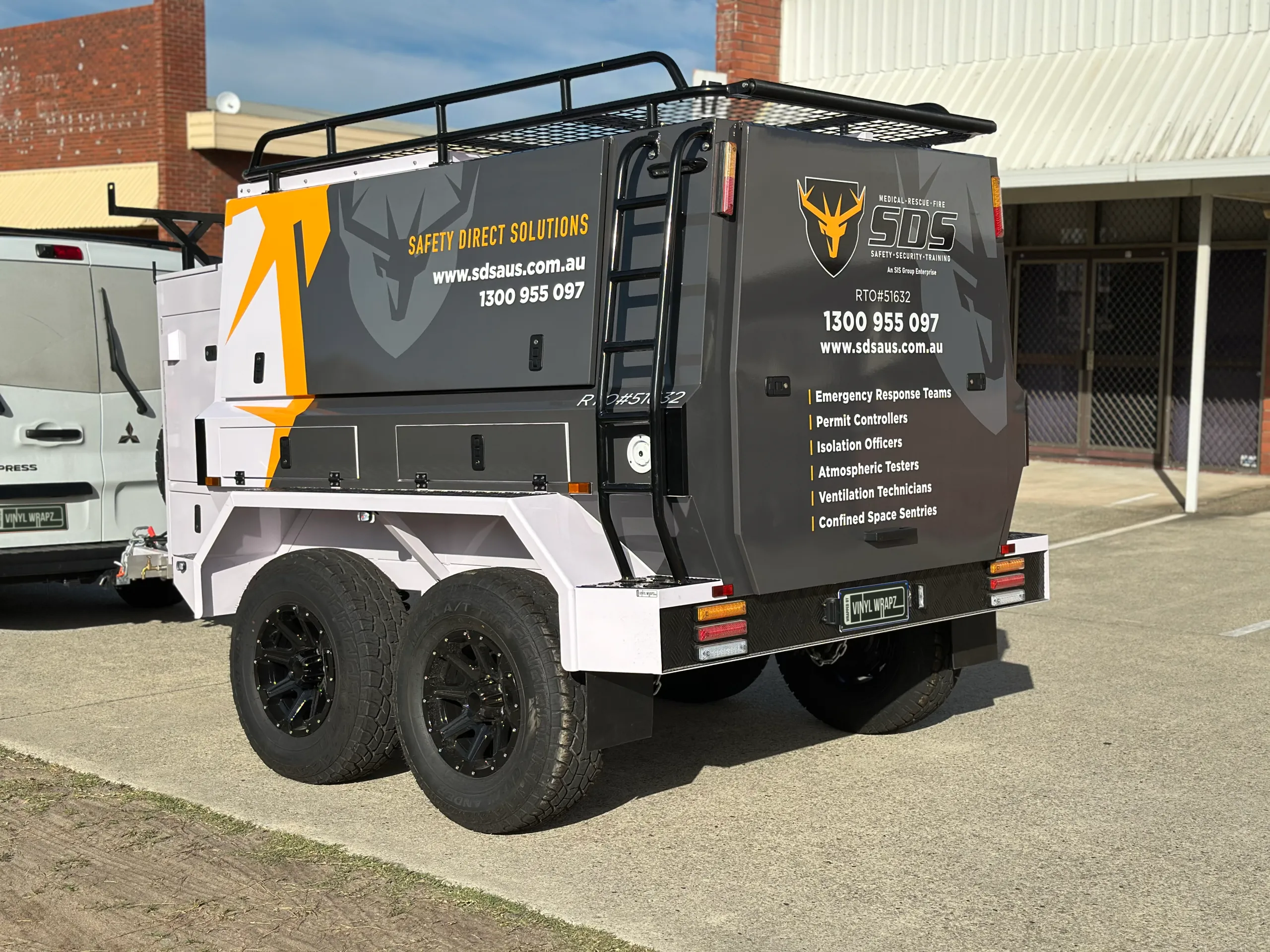 Grey SDS trailer with black wheels and a roof rack outside the workshop