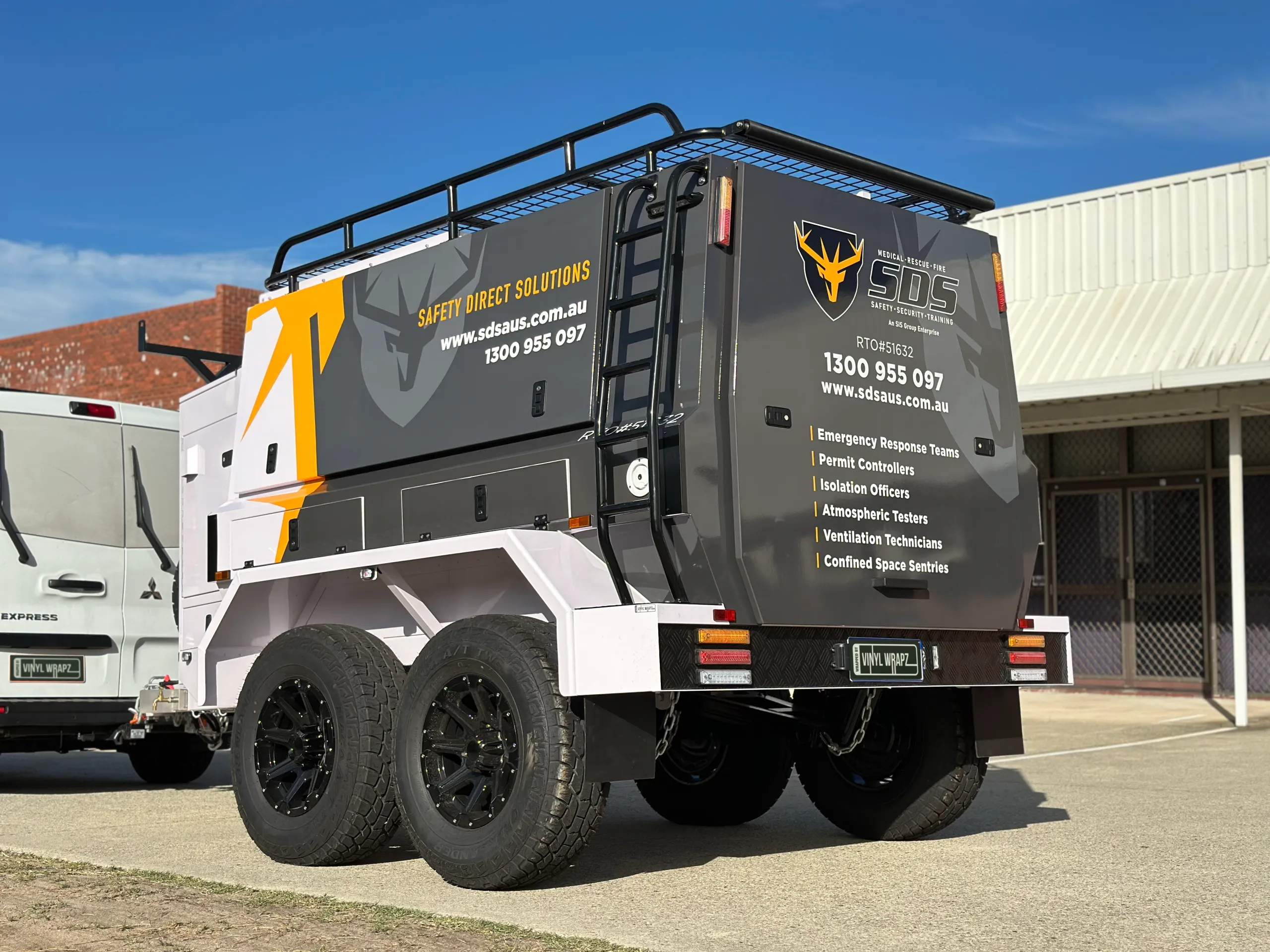 Low rear-quarter view of the SDS equipment trailer with grey and yellow branding