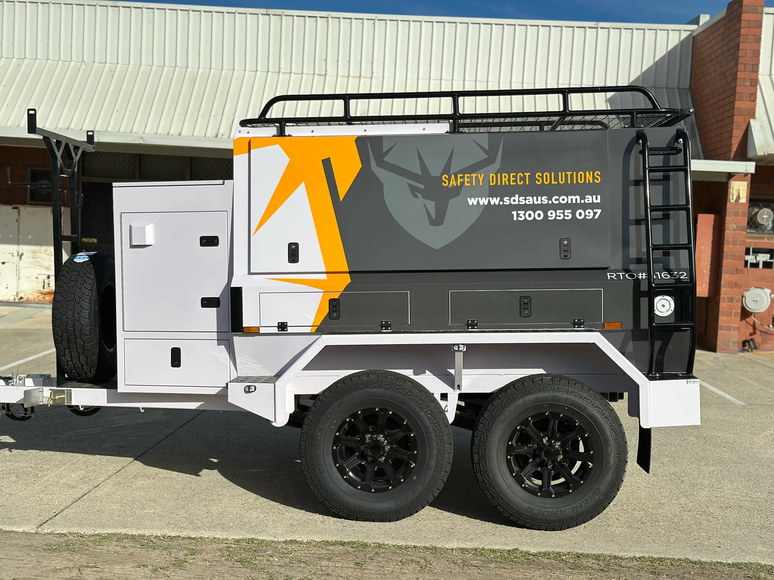 Side view of the grey and white SDS trailer with yellow graphics and black wheels