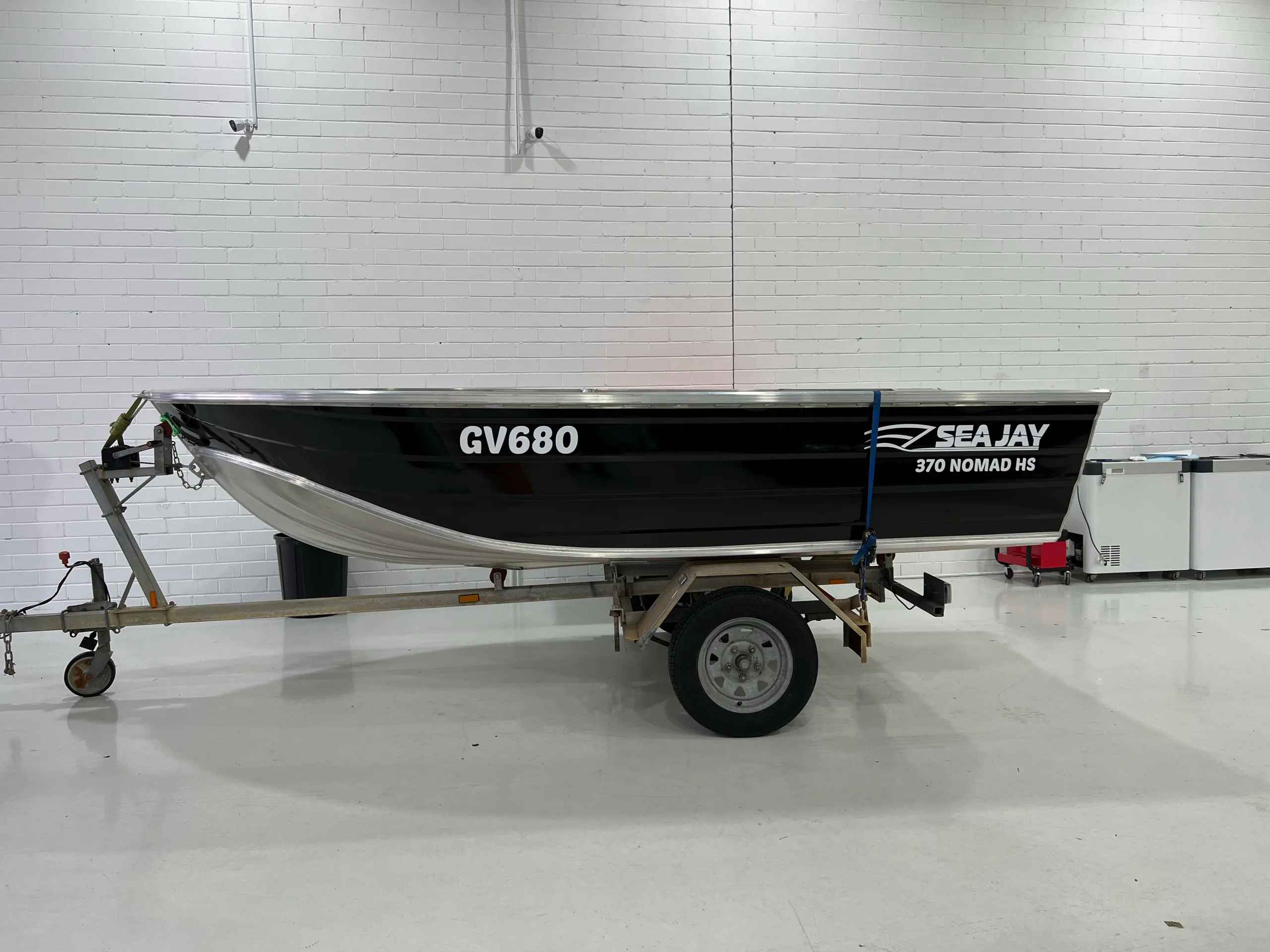Gloss black Sea Jay 370 Nomad HS dinghy on its trailer inside the workshop