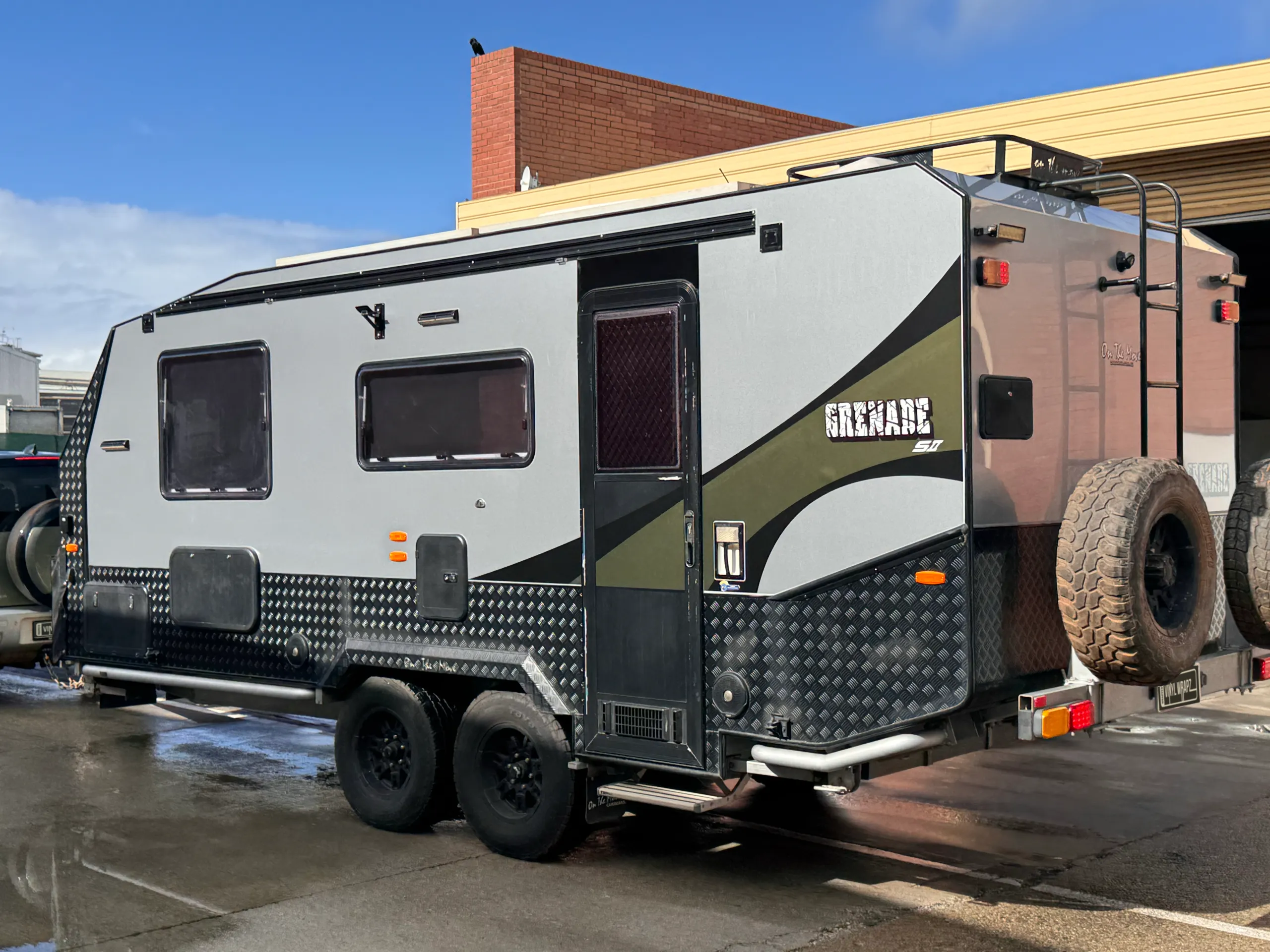 Silver and olive green caravan outside the workshop after its exterior refresh